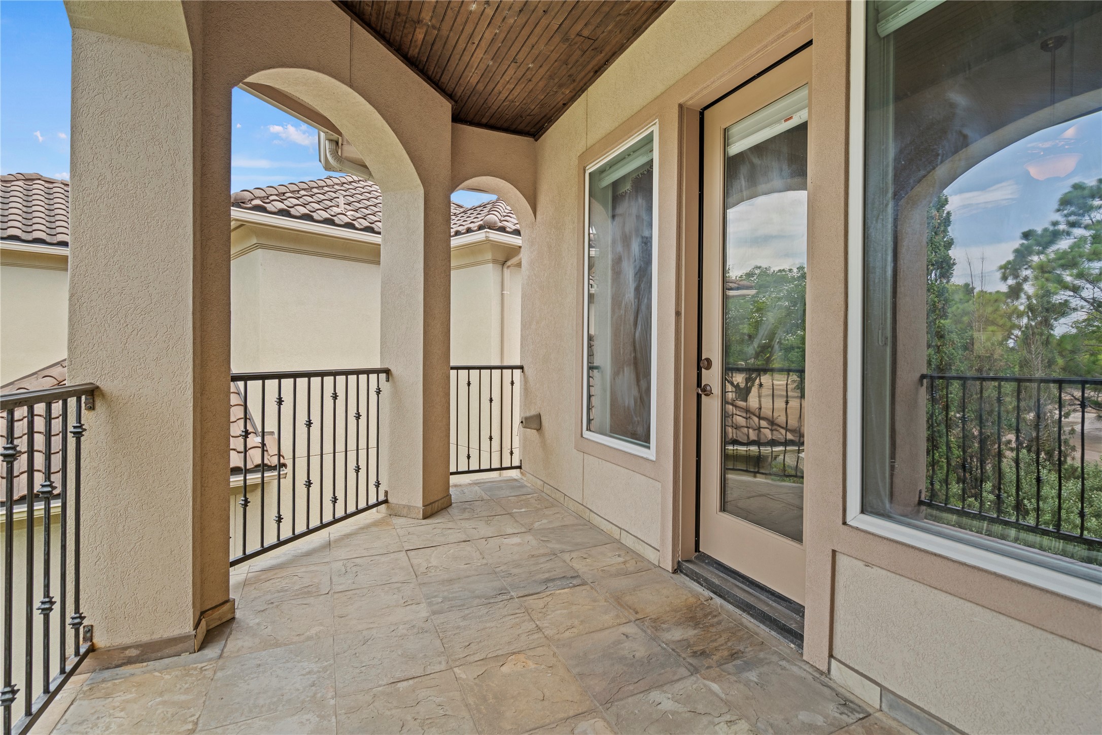 Covered upper-level balcony with arched openings, tile flooring, and scenic views of the surrounding landscape.