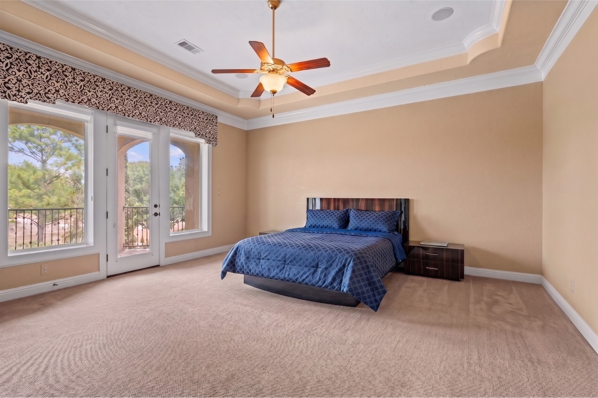 Forth bedroom featuring a tray ceiling, crown molding, plush carpeting, and French doors opening to a private balcony.