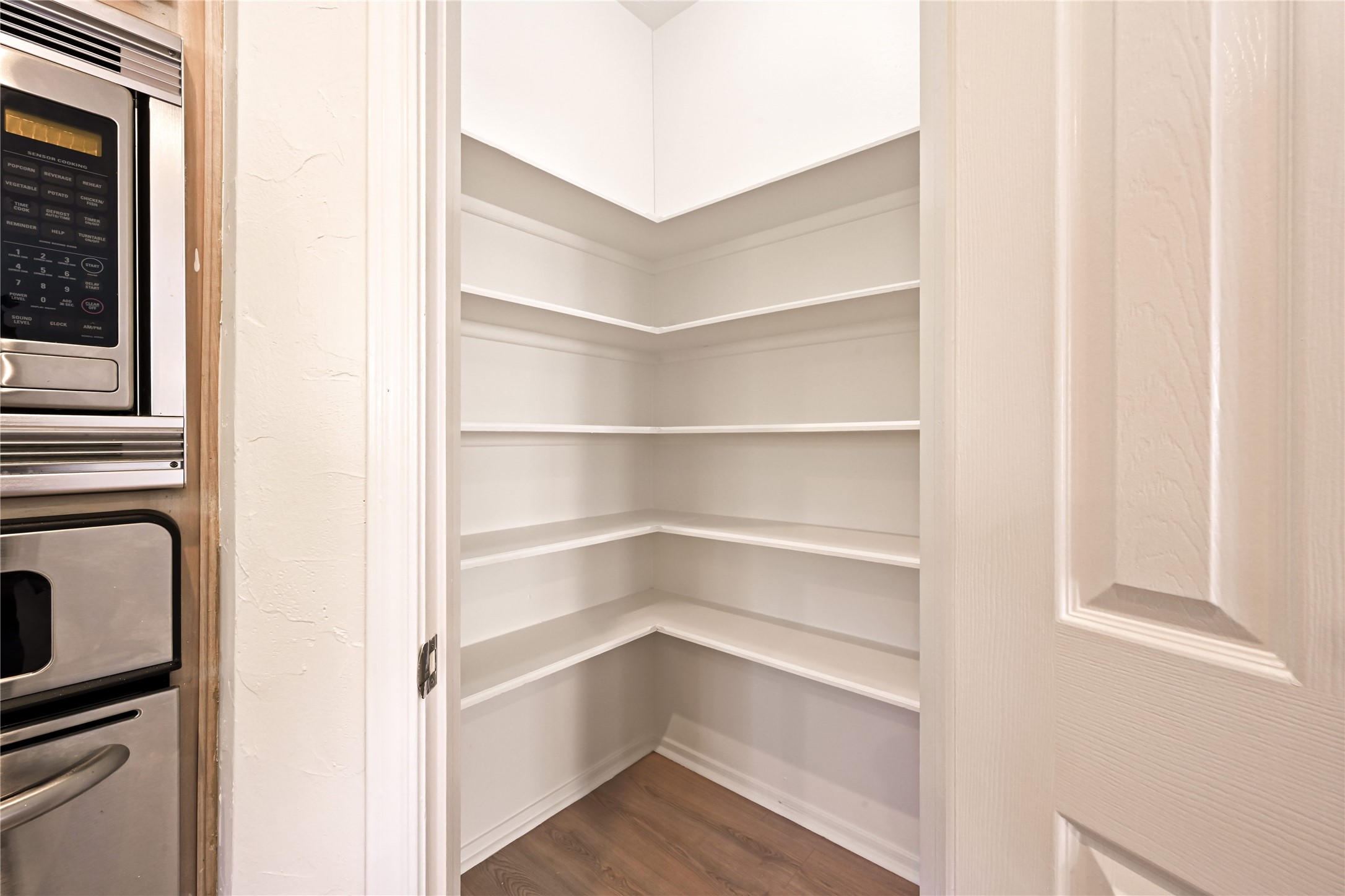 Walk-in pantry with ample shelving for organized storage, conveniently located next to the kitchen appliances.