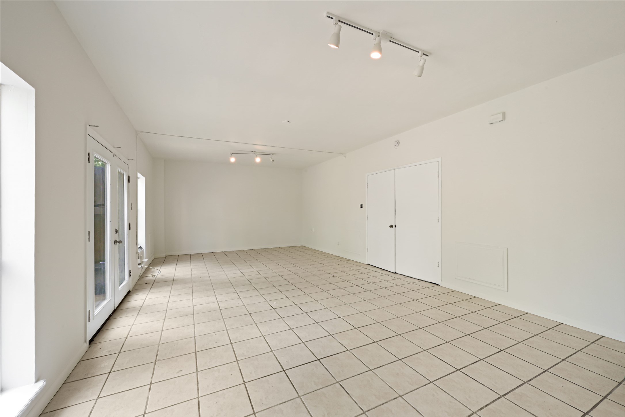 Light-filled room with tiled flooring and French doors opening to the outside, perfect for versatile living or entertaining.