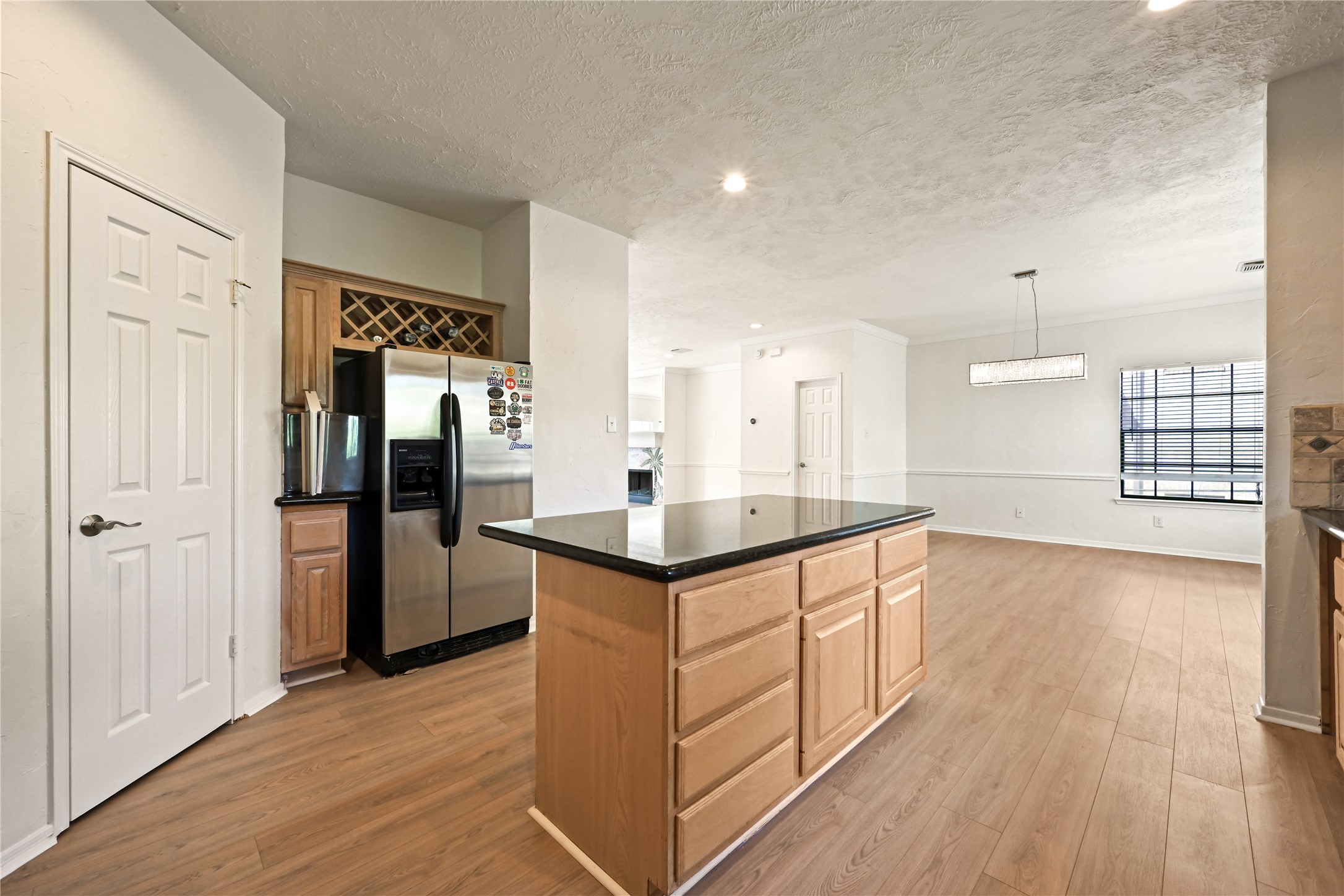 Open kitchen and dining area featuring sleek hardwood floors, a modern stainless steel refrigerator, and a large island with ample storage.