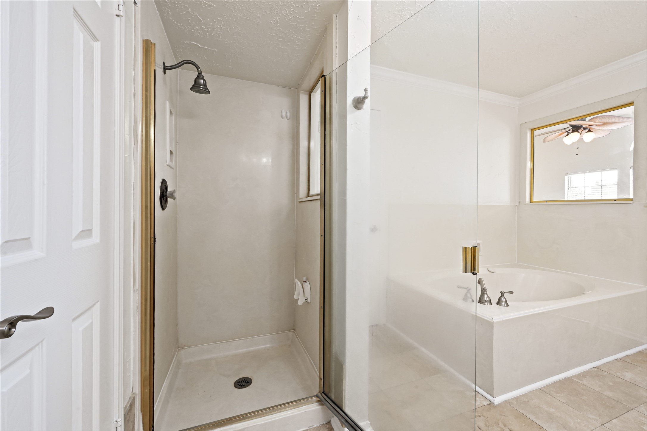 Bathroom features a glass-enclosed shower and a large soaking tub, offering a serene retreat with sleek fixtures and neutral tones.