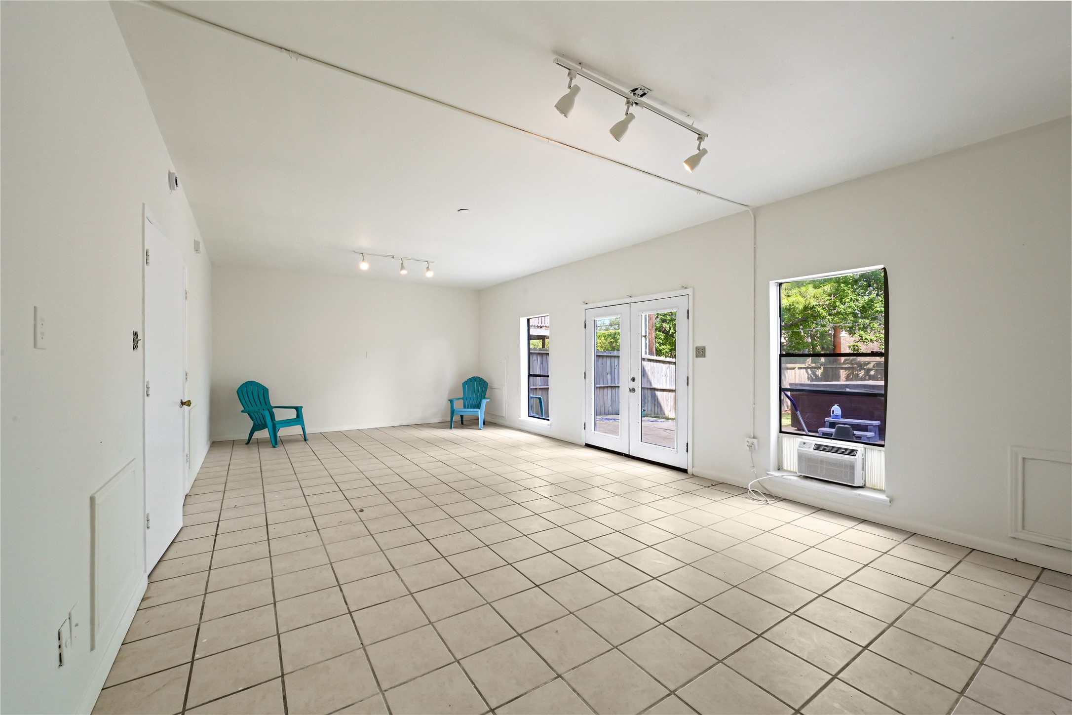 Spacious and bright living area with tile flooring, featuring large windows and a door leading to the outdoor space, perfect for gatherings.