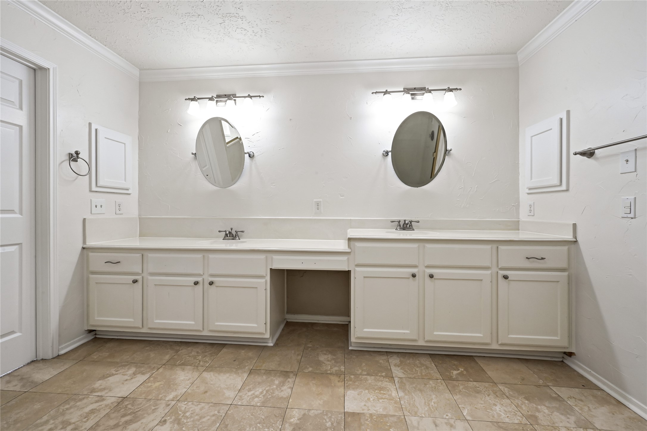 Spacious bathroom with dual sinks, elegant oval mirrors, and ample cabinetry, all complemented by stylish tile flooring.