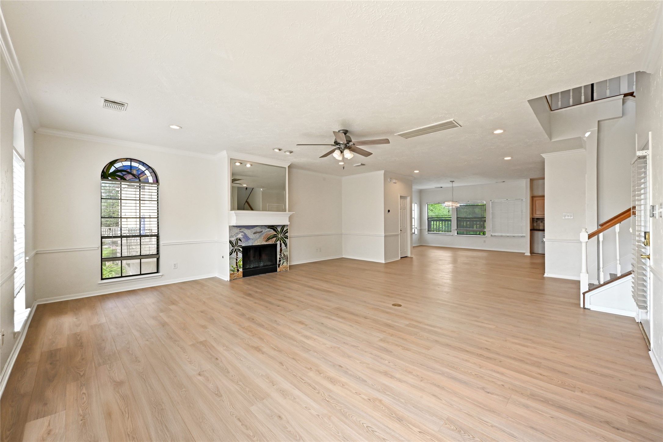Open-concept living area with elegant wood flooring, a cozy fireplace, and abundant natural light from large windows.