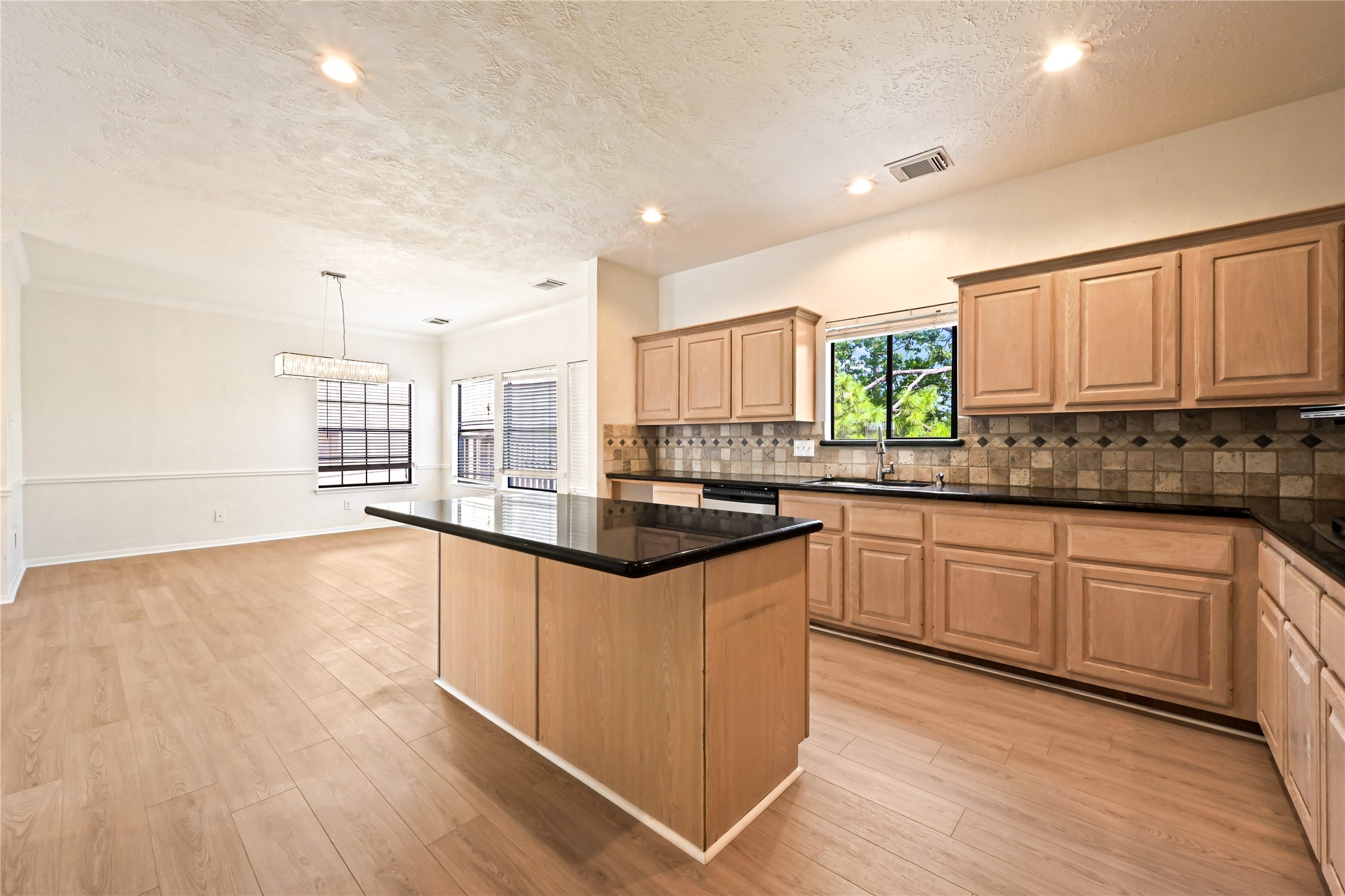 Spacious open-concept kitchen and dining area featuring sleek black countertops, ample cabinetry, and abundant natural light.