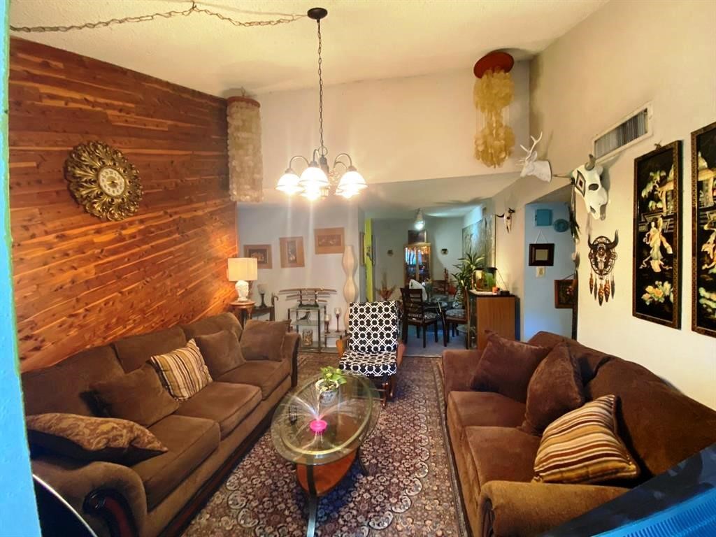 Cozy living room with warm wood accents, plush brown sofas, and eclectic decor. Features a unique wood-paneled wall, ambient lighting, and an inviting atmosphere. Perfect for relaxation and entertaining.