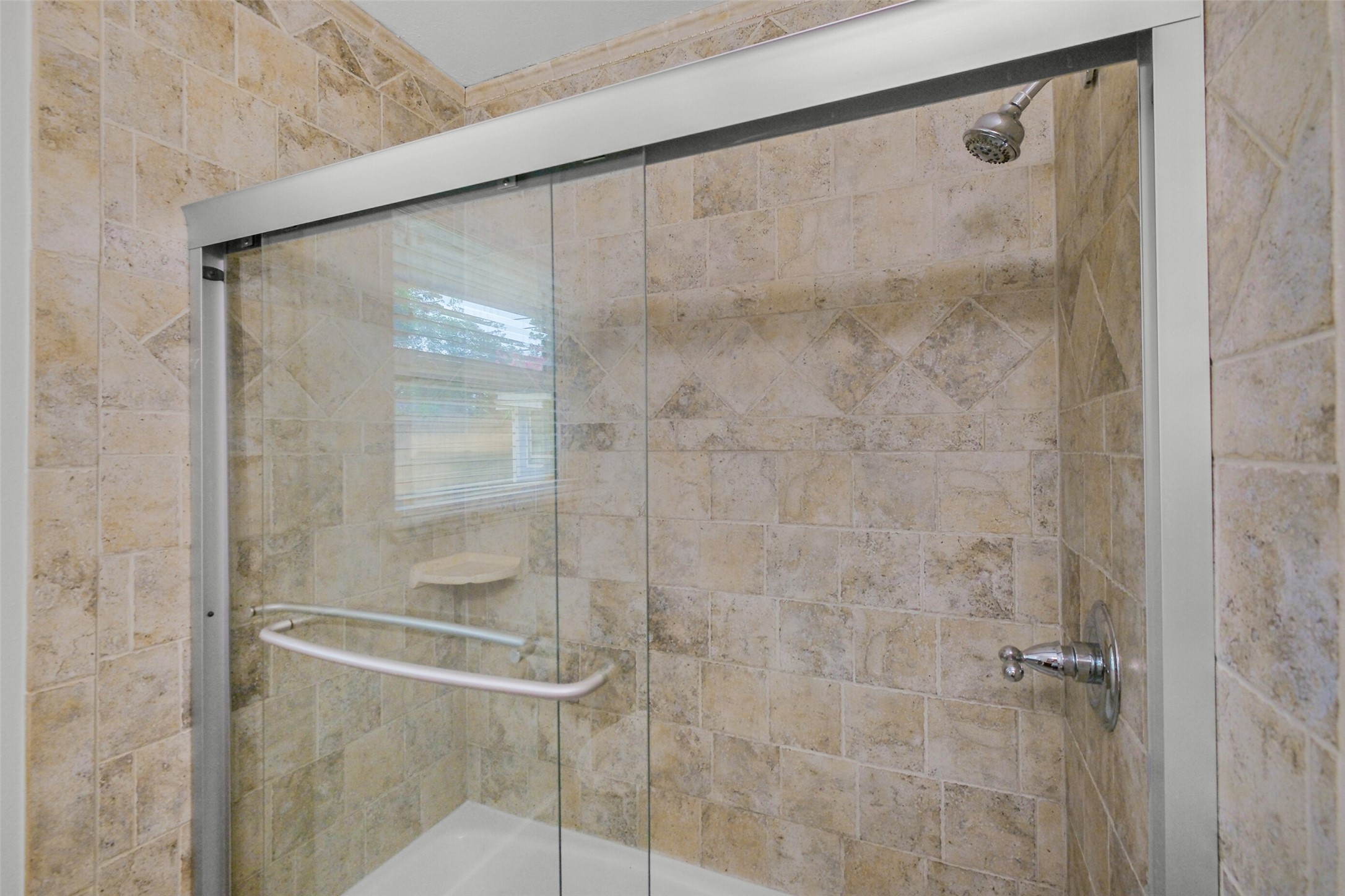 Updated glass enclosed bath/shower serving second bedroom.