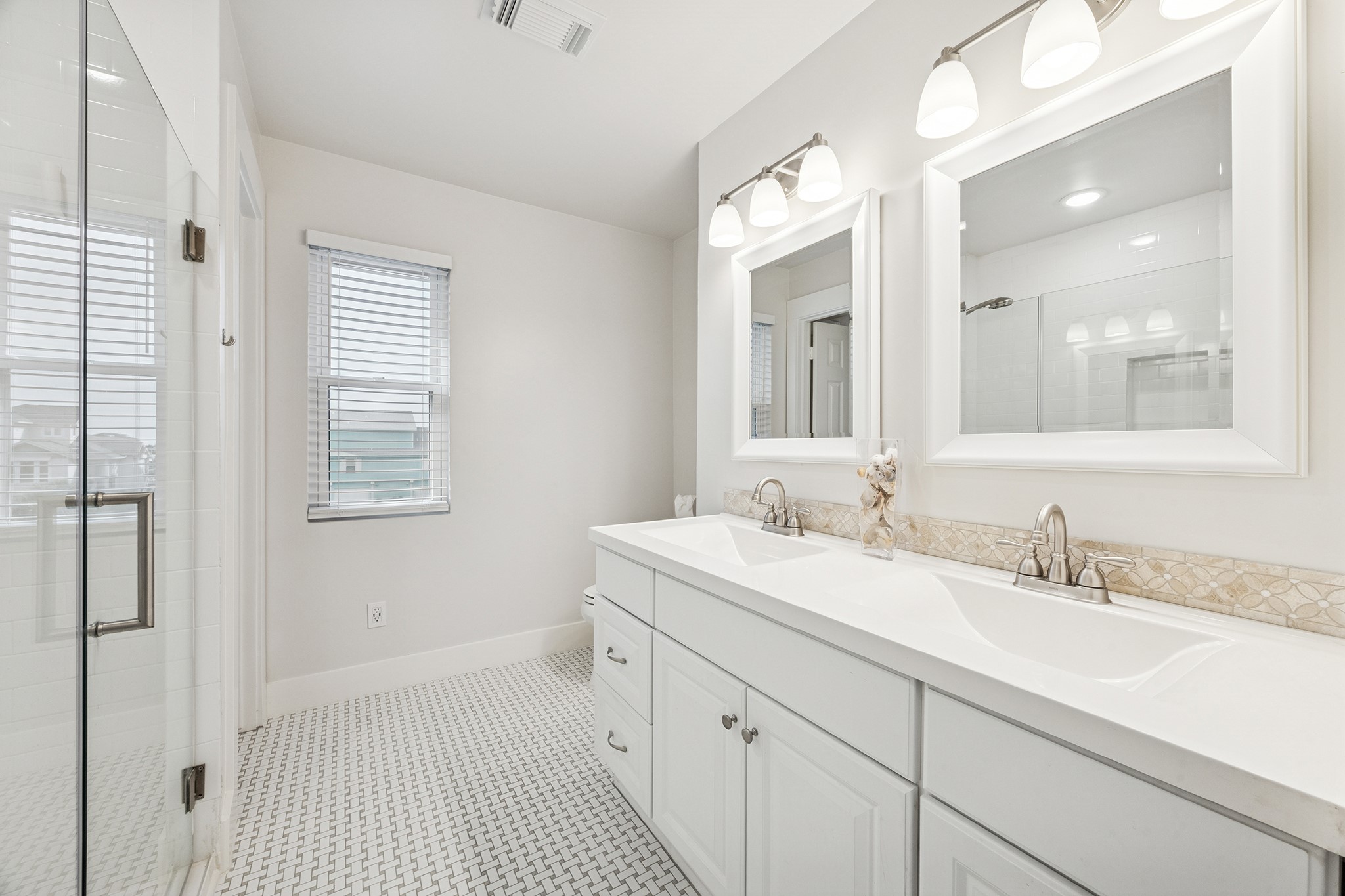 Experience luxury in this pristine primary bath, featuring a spacious double vanity, elegant lighting, and a sleek glass shower, perfect for unwinding in style.