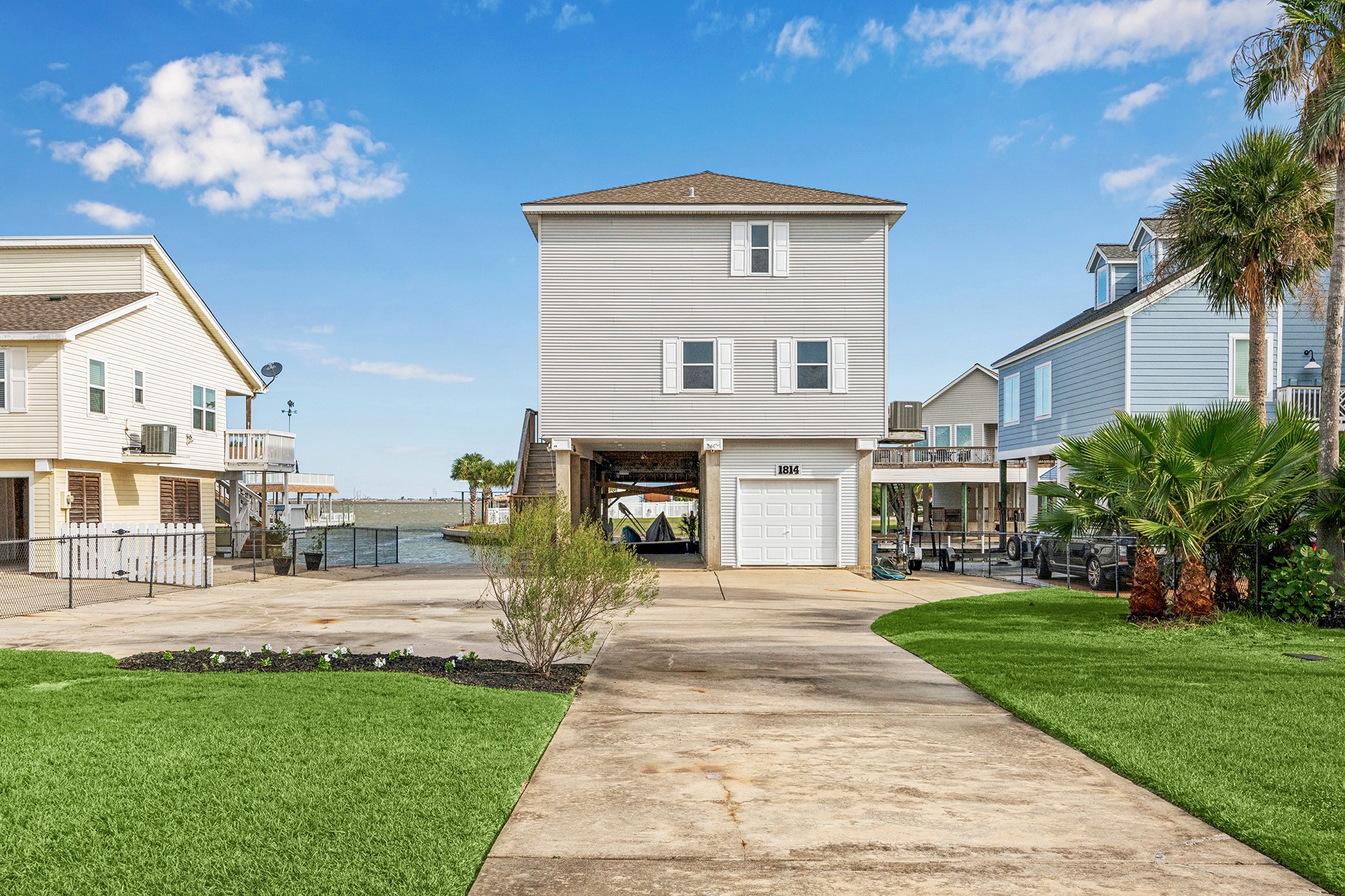 Nestled by the water, this charming three-story home boasts a spacious driveway, lush greenery, and a welcoming facade, offering picturesque waterfront living.
