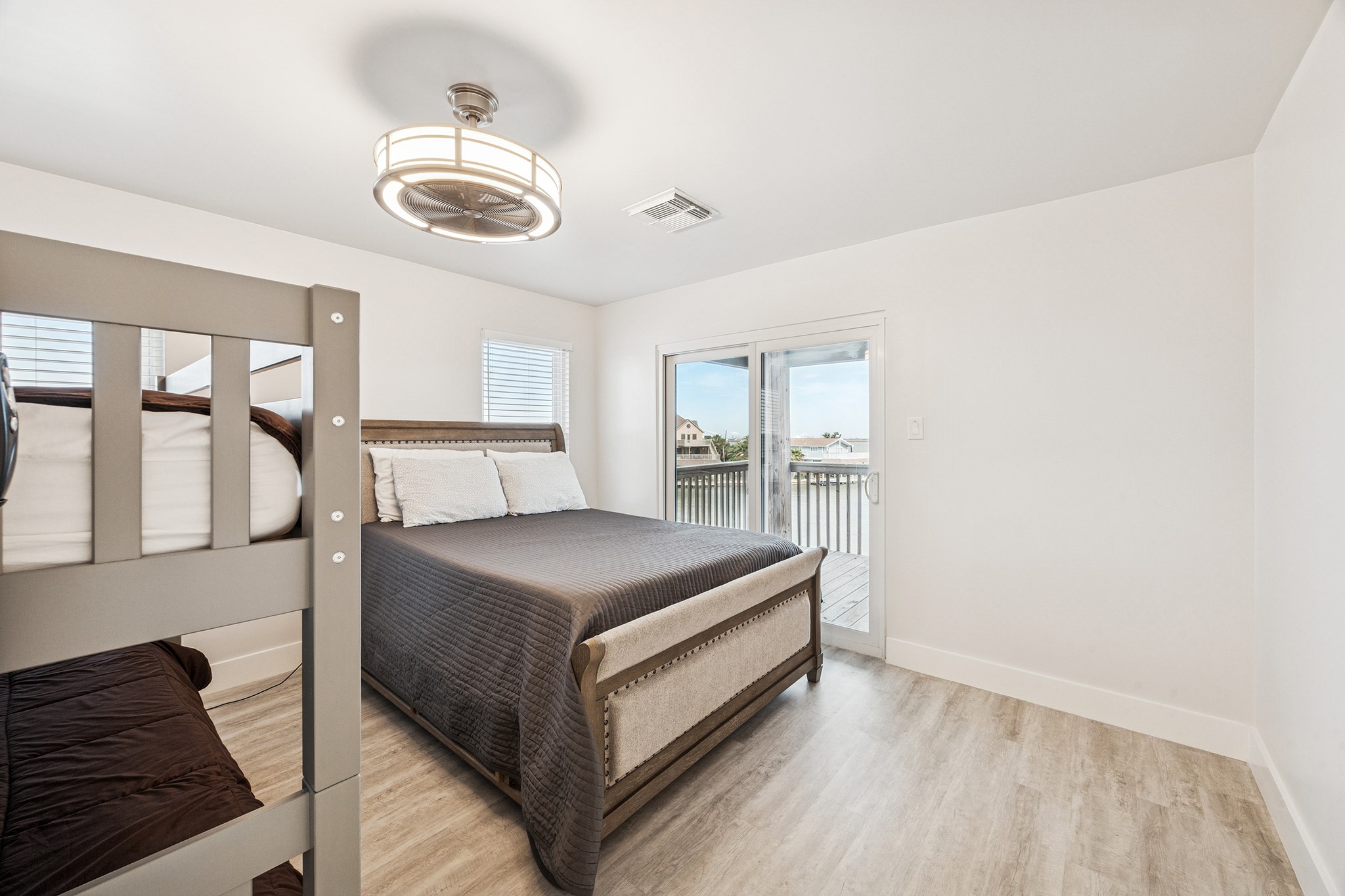 Discover a bright, inviting bedroom featuring sleek flooring, a cozy bed, and glass doors opening to serene water viewsyour perfect retreat.