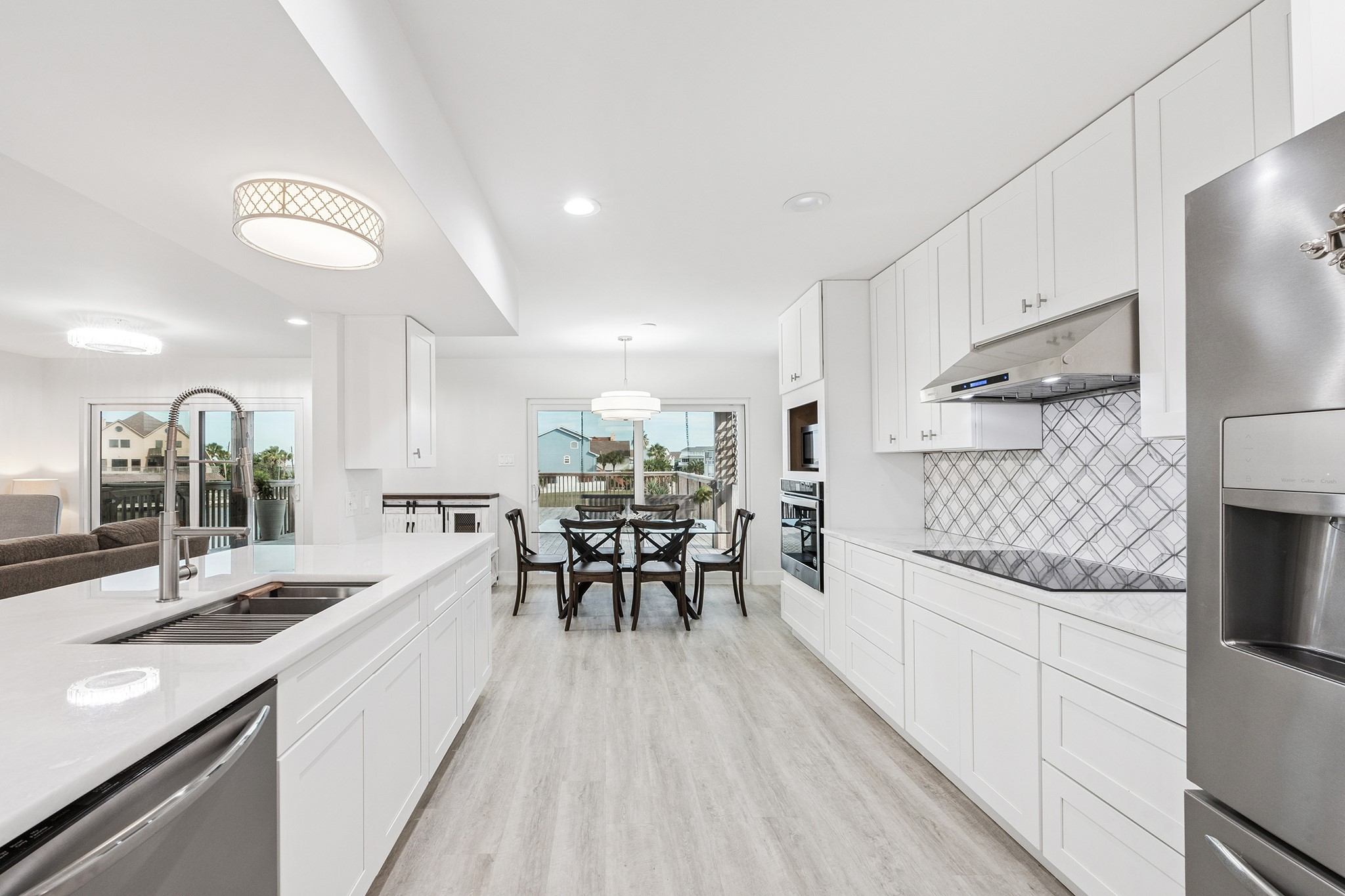 This kitchen offers a bright, modern space with sleek white cabinetry, stainless steel appliances, and an inviting open layout perfect for entertaining and family gatherings.