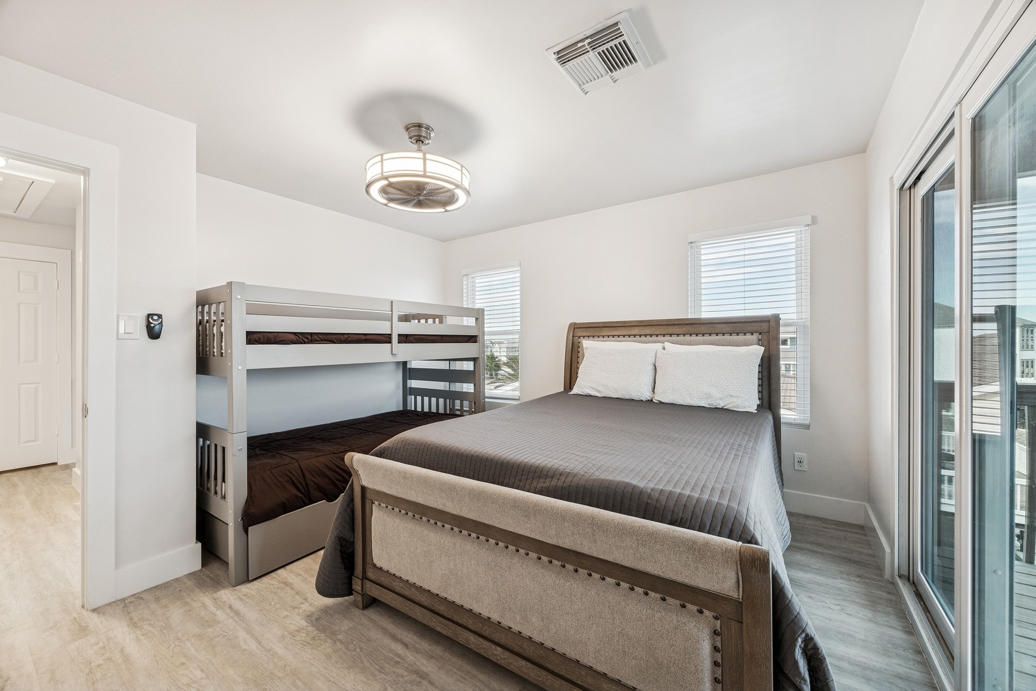 This bright and inviting bedroom offers ample space with a cozy bed and stylish bunk beds, perfect for relaxation and family comfort.
