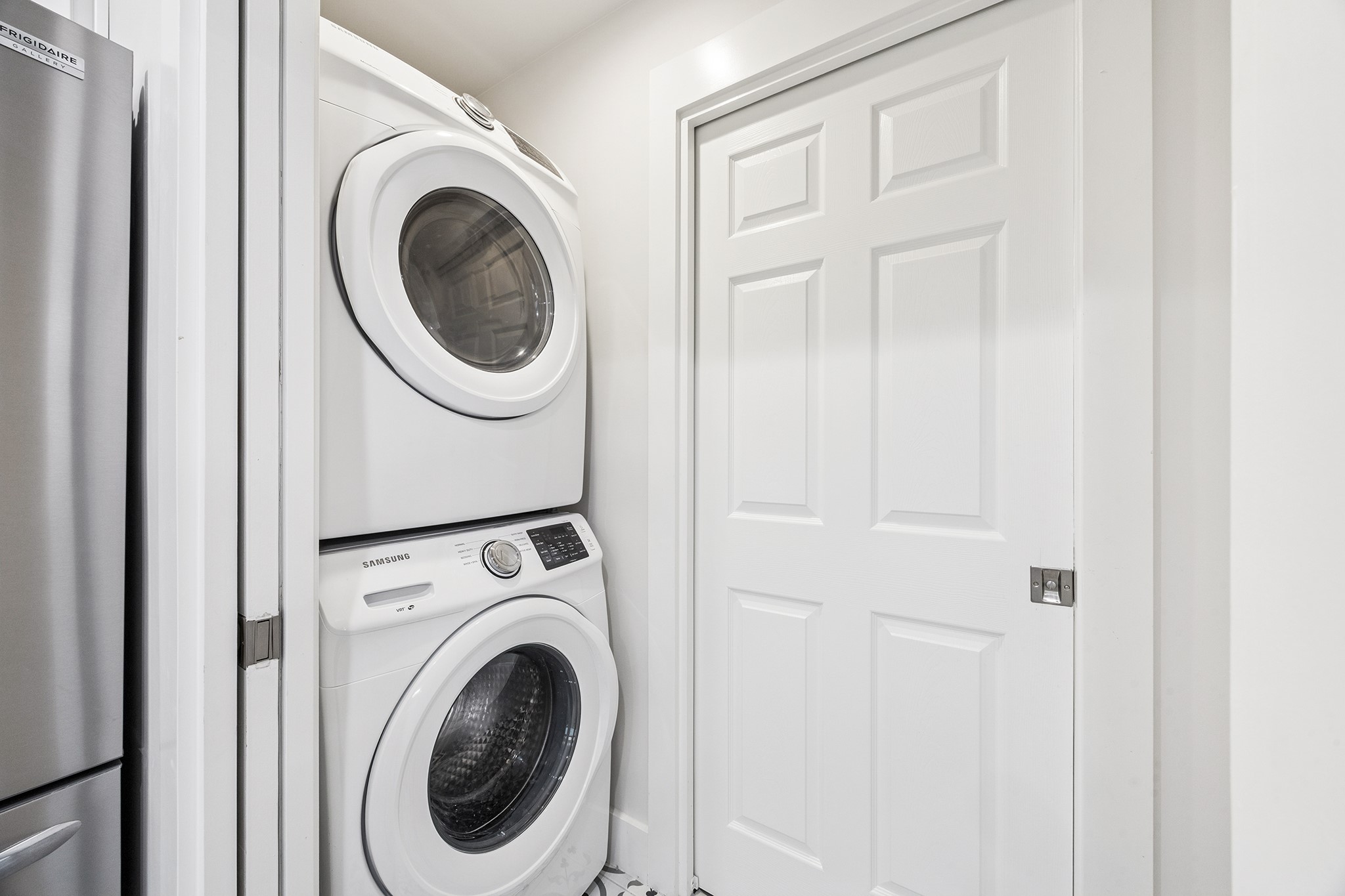 This washroom boasts a sleek, space-saving design with modern stacked laundry appliances, perfect for efficient living.