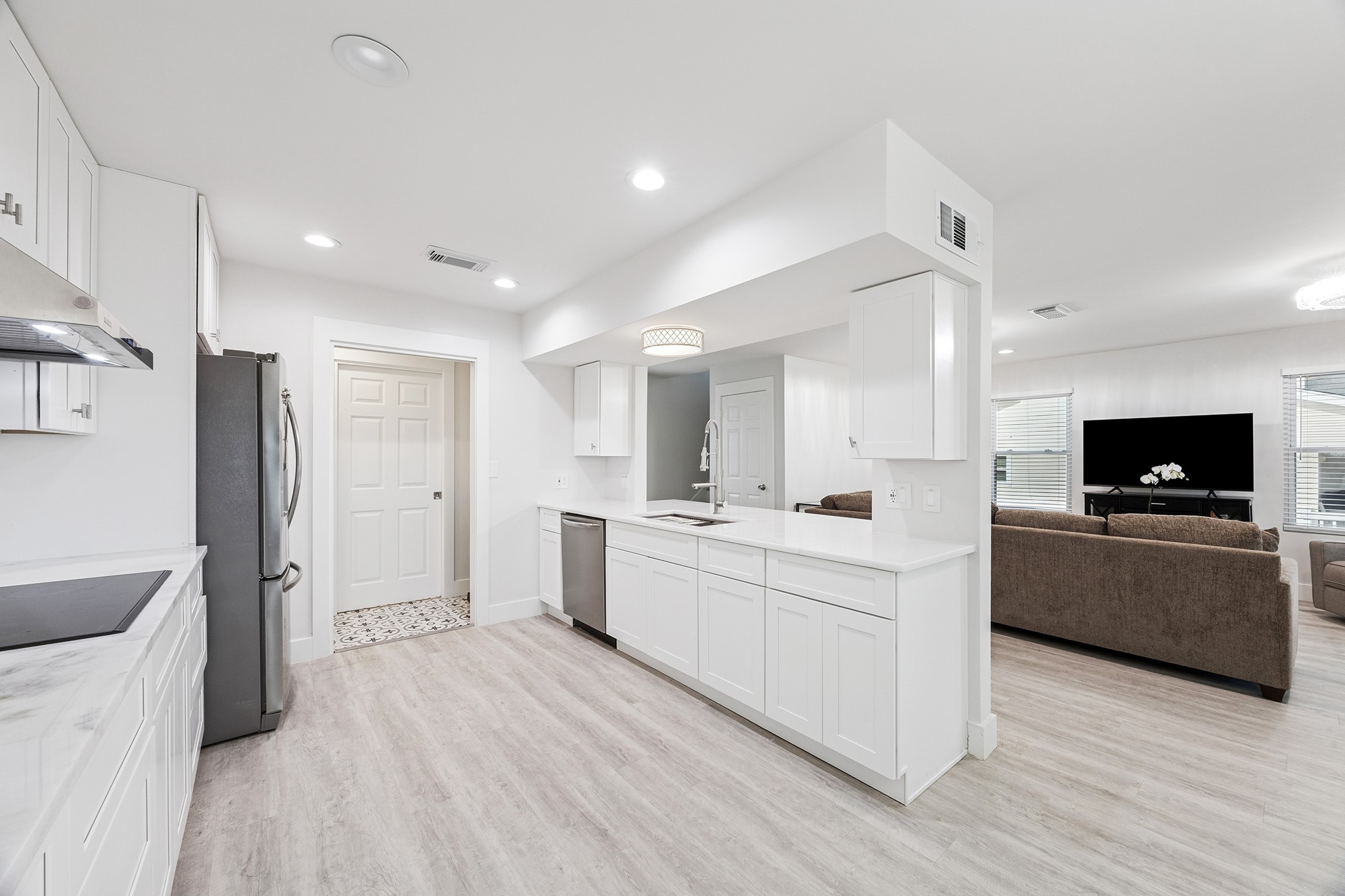 This bright, modern kitchen features sleek white cabinetry, stainless steel appliances, and an open layout that seamlessly connects to a cozy living areaperfect for entertaining and everyday living.