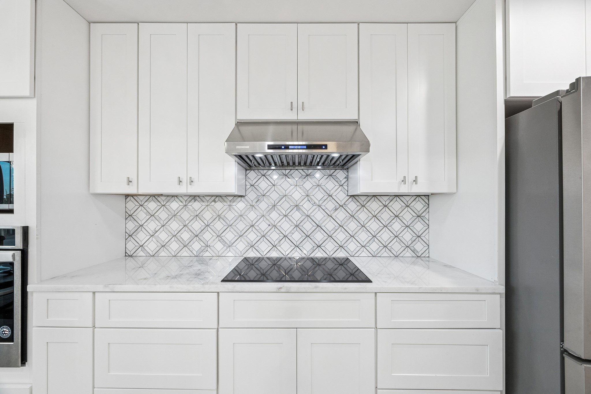 Discover culinary elegance with this sleek kitchen cooktop, set against a stylish backsplash and surrounded by ample storage, perfect for inspiring your inner chef.