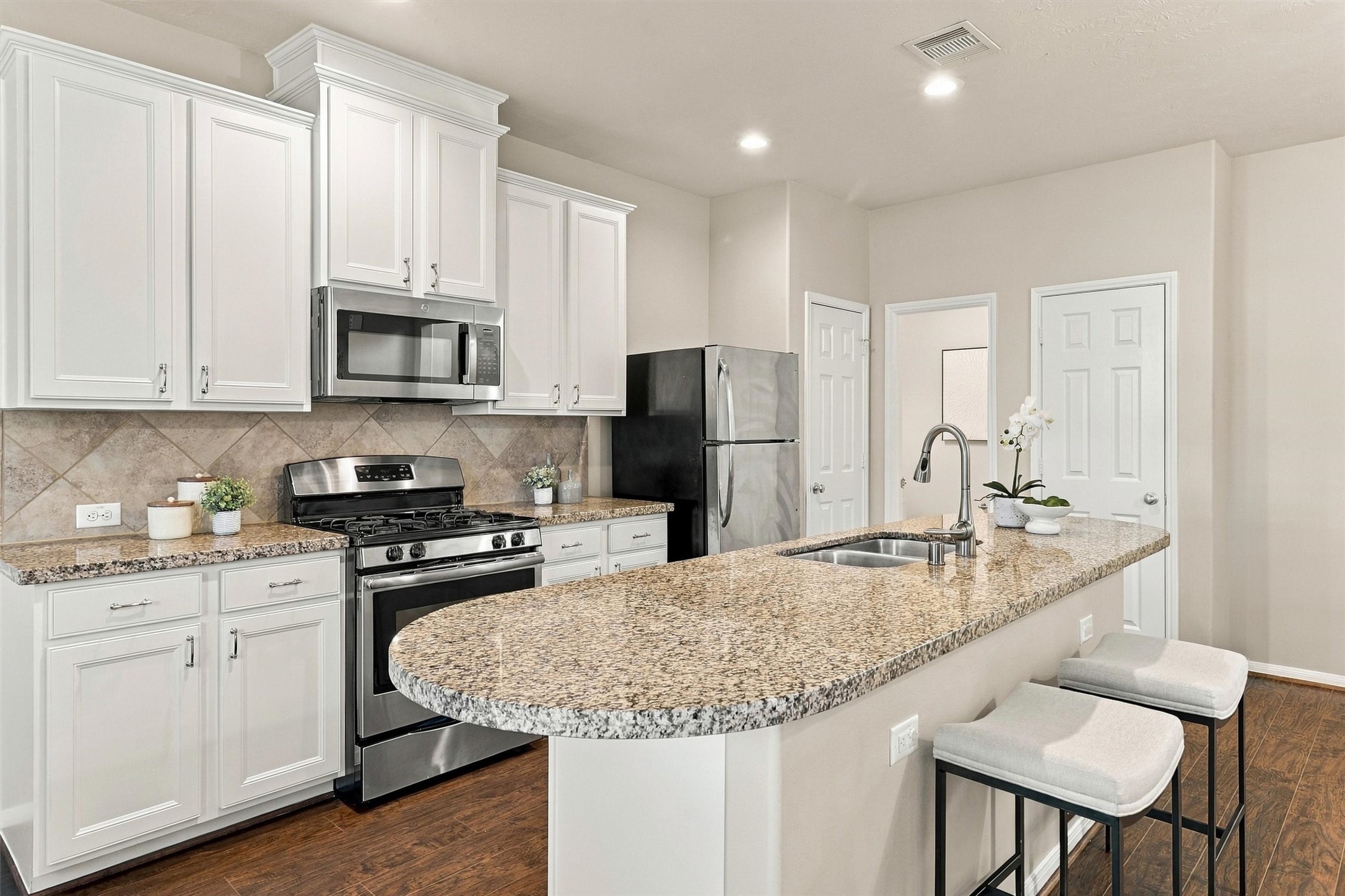 Pull bar stools up to your kitchen island for an alternative space to dine. Note the pantry to the right of the fridge.  The half bathroom is in the corner, and the door to the right is a large walk-in storage closet.