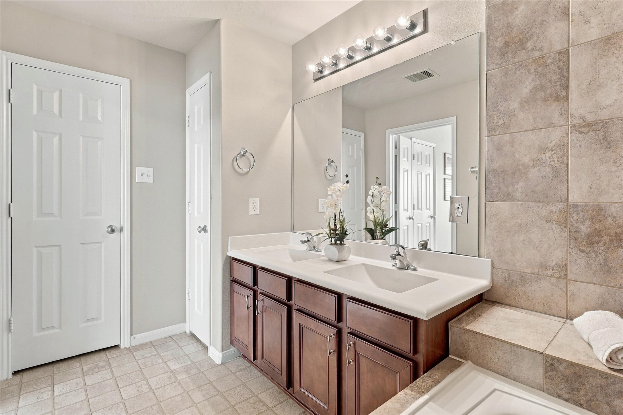 The primary bathroom has a linen closet to the left of the sinks for even more storage. The commode is conveniently tucked behind a door for privacy.