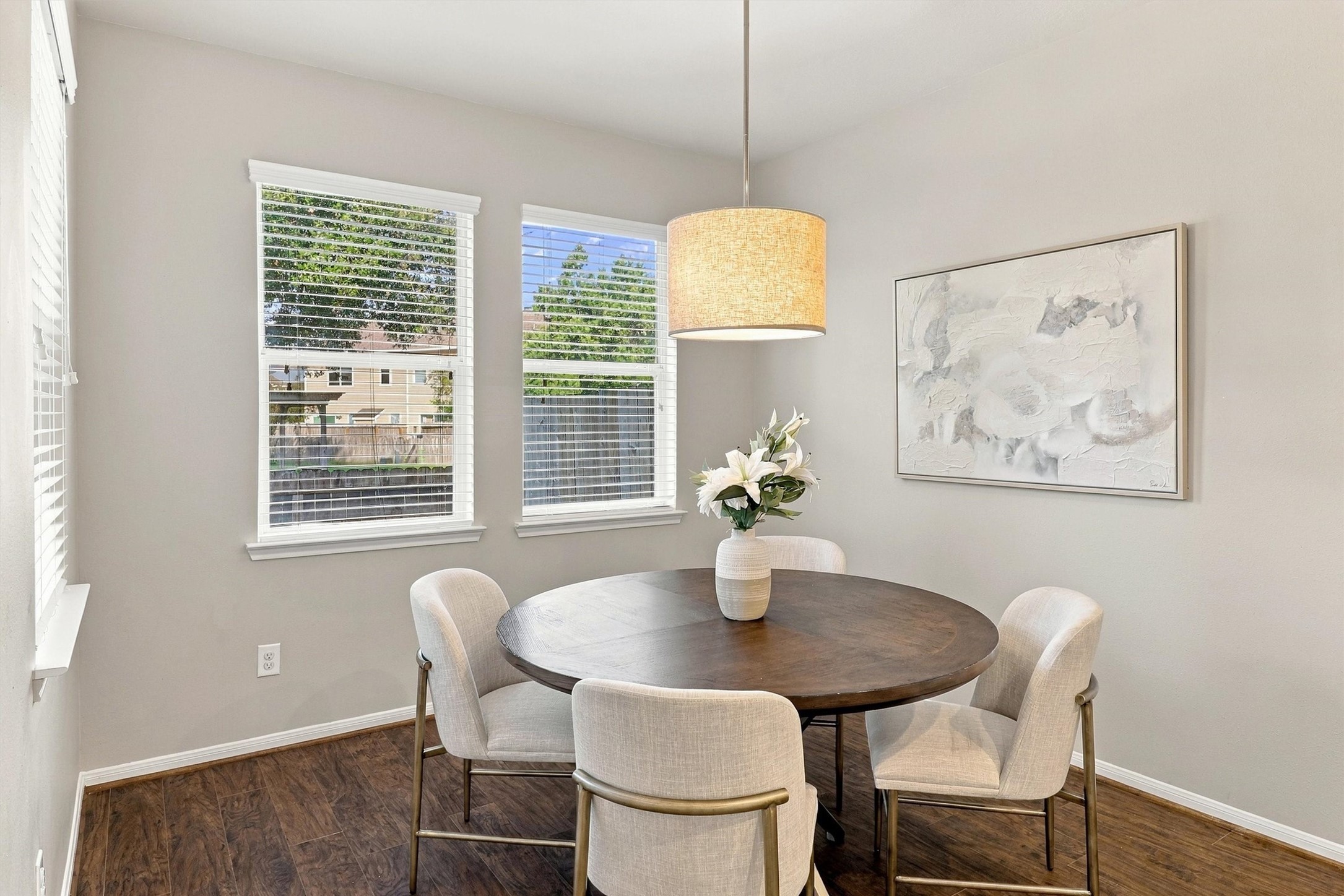 Center your table beneath the elegant drum shade pendant light.  Sherwin Williams paint, crisp white trim, and rich wood-look floors complete the space.