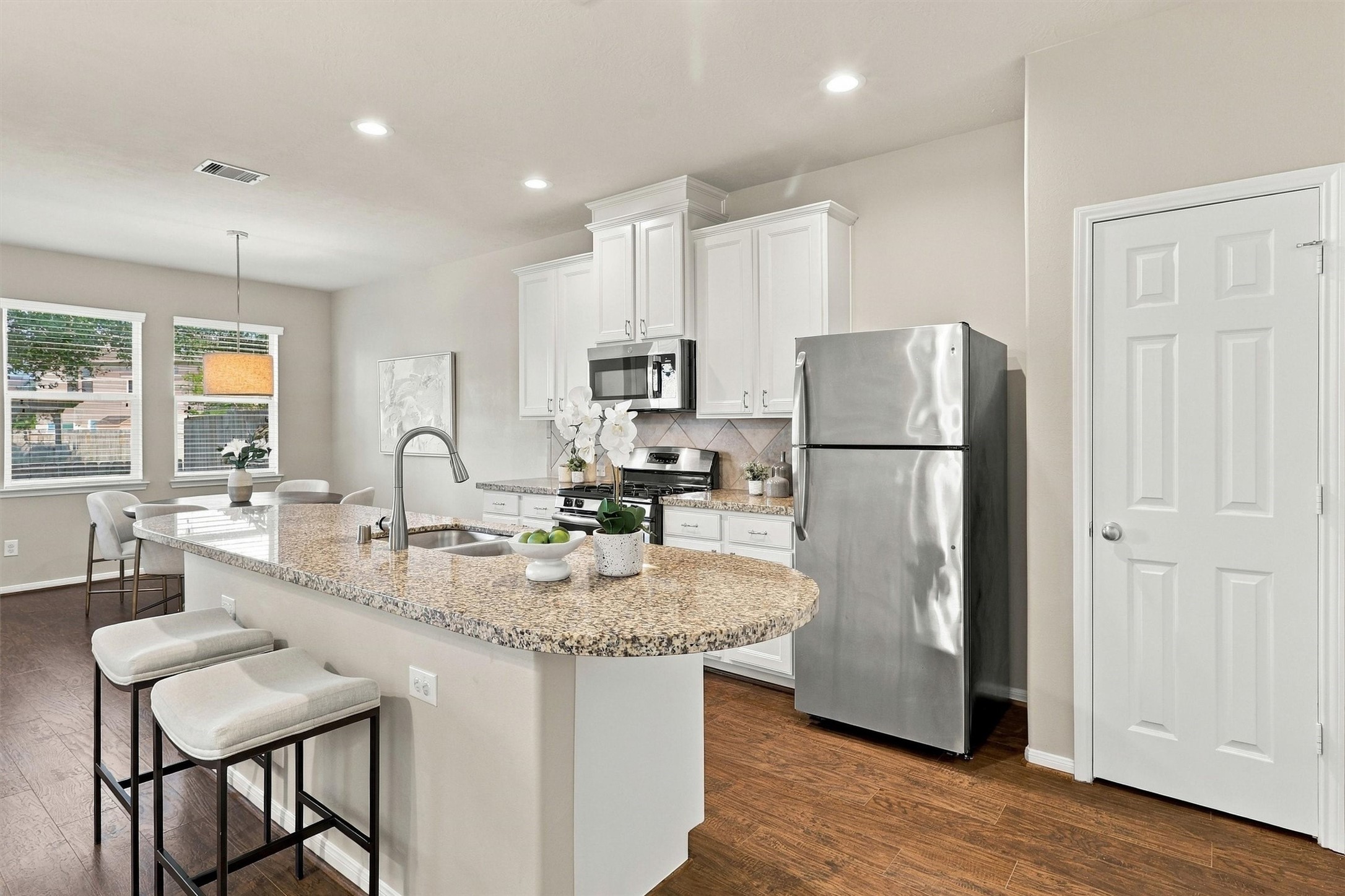 Welcome to your PRISTINE and elevated kitchen! The cabinets are in perfect condition and are painted a soft white with top quality Sherwin Williams Paint. Note the granite counters, recessed lighting, tile backsplash, undermount sink, and brushed nickel finishes that complement the stainless steel appliances.  The cabinets are upgraded with a staggered elevation, crown molding, and nickel cabinet pulls.