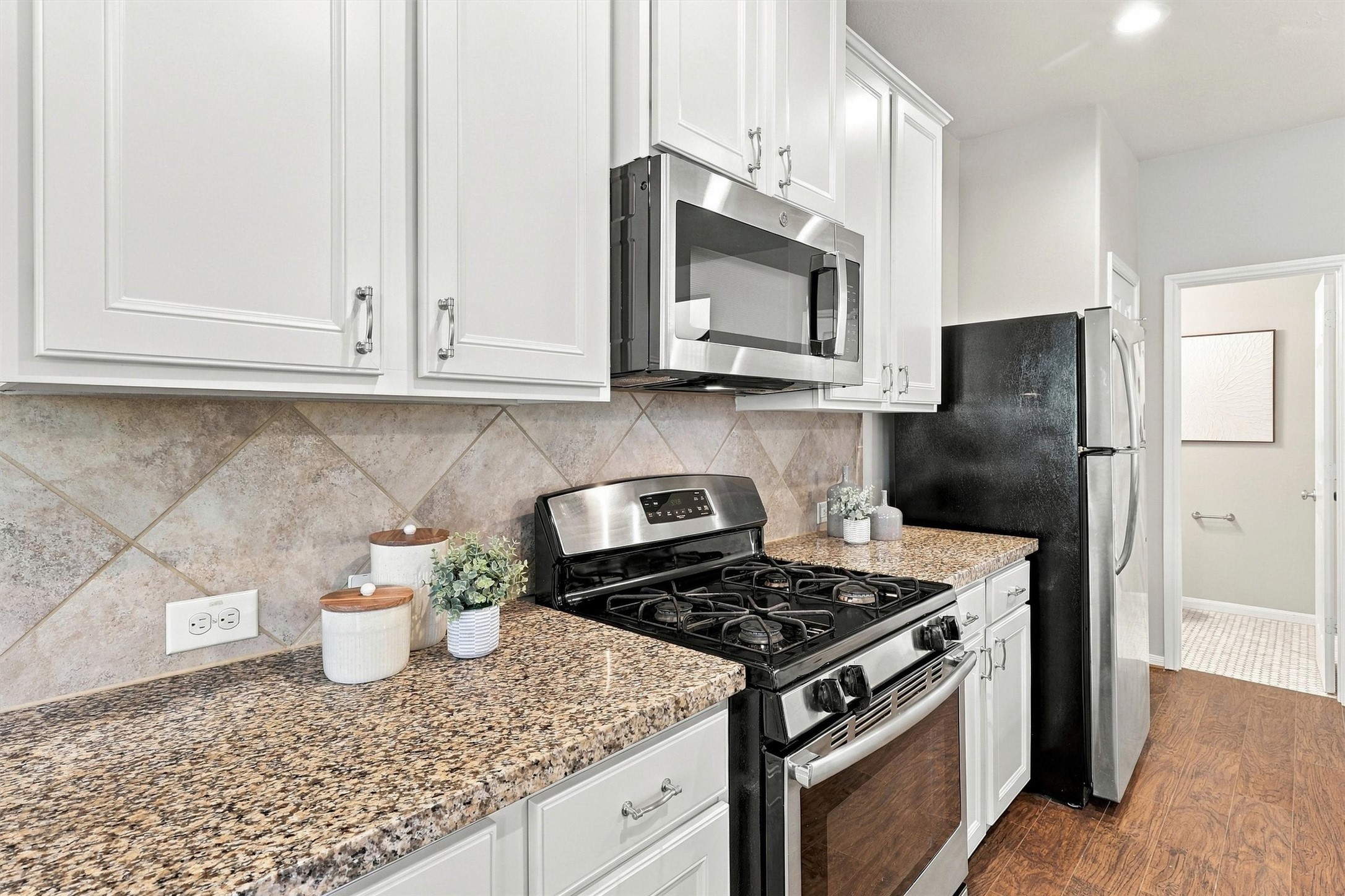 The solid wood cabinets feature a delicate bevel on the drawer and door fronts. The tile backsplash, granite counters, paint, nickel finishes, and stainless steel appliances create a cohesive palette.