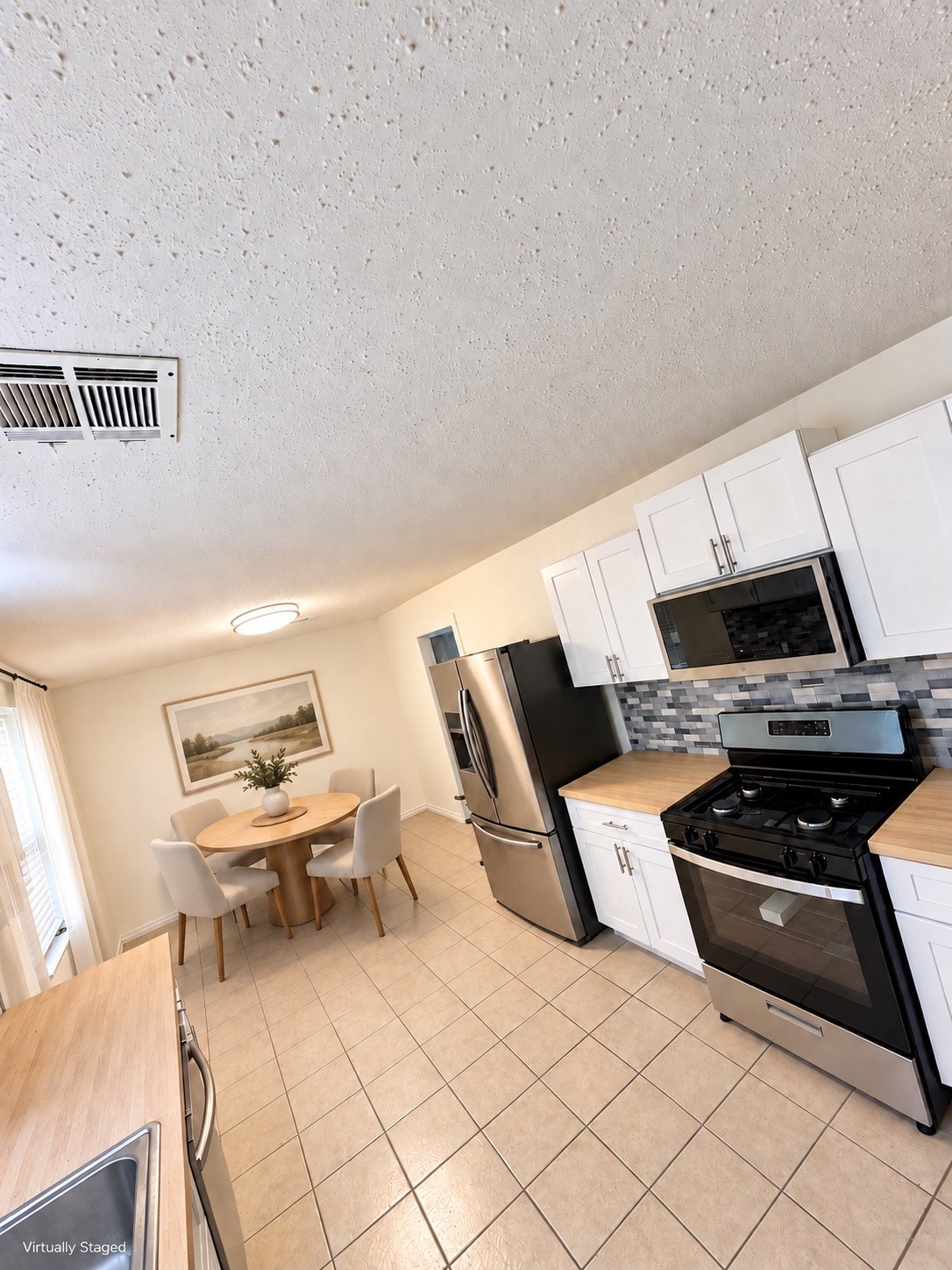 Bright and inviting kitchen featuring modern stainless steel appliances, ample cabinetry, and a cozy dining area perfect for family gatherings.