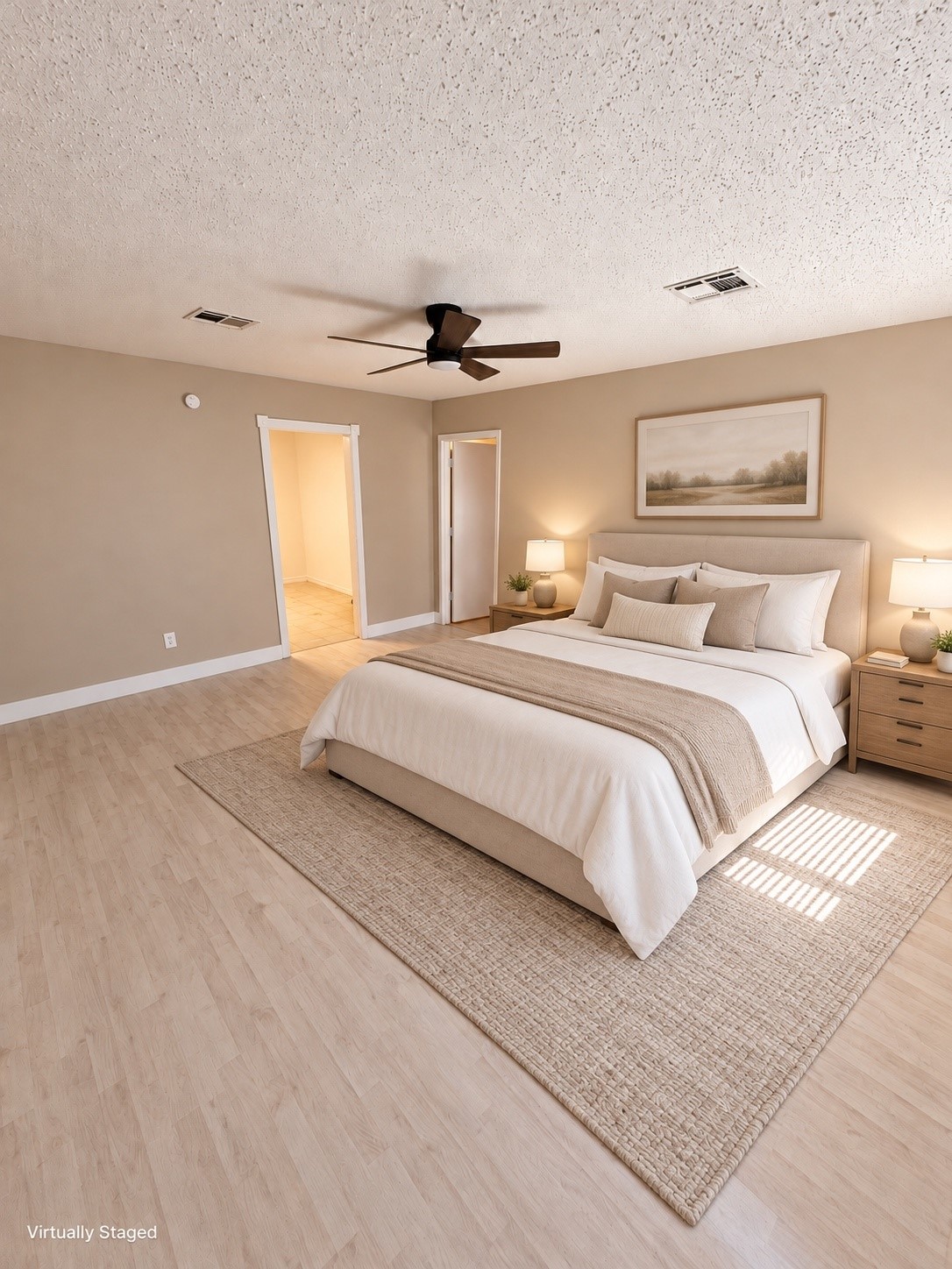 Spacious bedroom with soft, neutral tones, featuring a cozy bed, modern ceiling fan, and ample natural light.