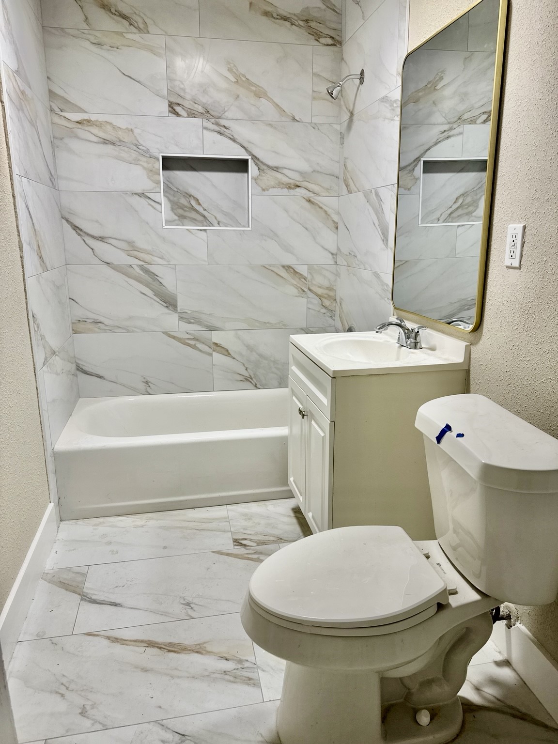 Elegant bathroom featuring modern marble tilework, a sleek vanity, and a spacious tub-shower combo.