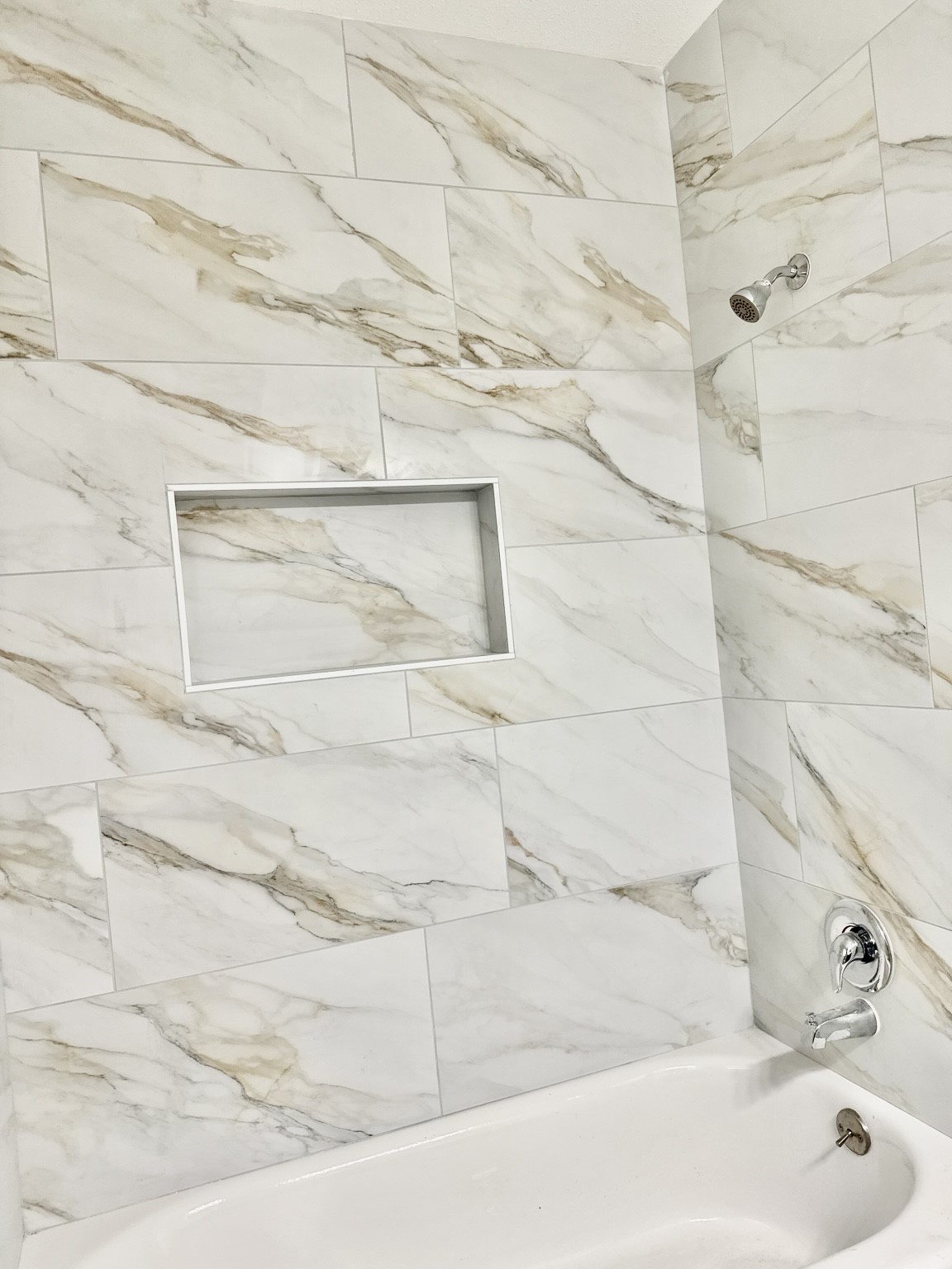 Elegant bathroom featuring a luxurious marble-tiled shower with a built-in niche and modern chrome fixtures.