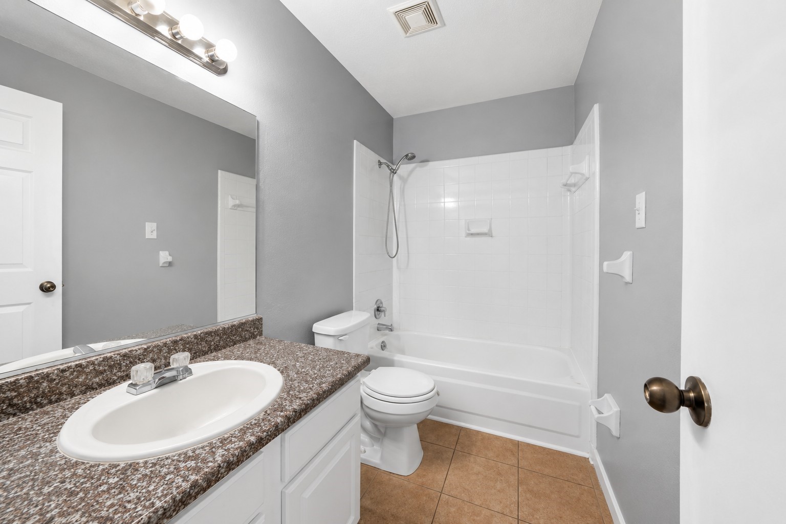 Shared full bathroom featuring a spacious vanity and tub/shower combination.