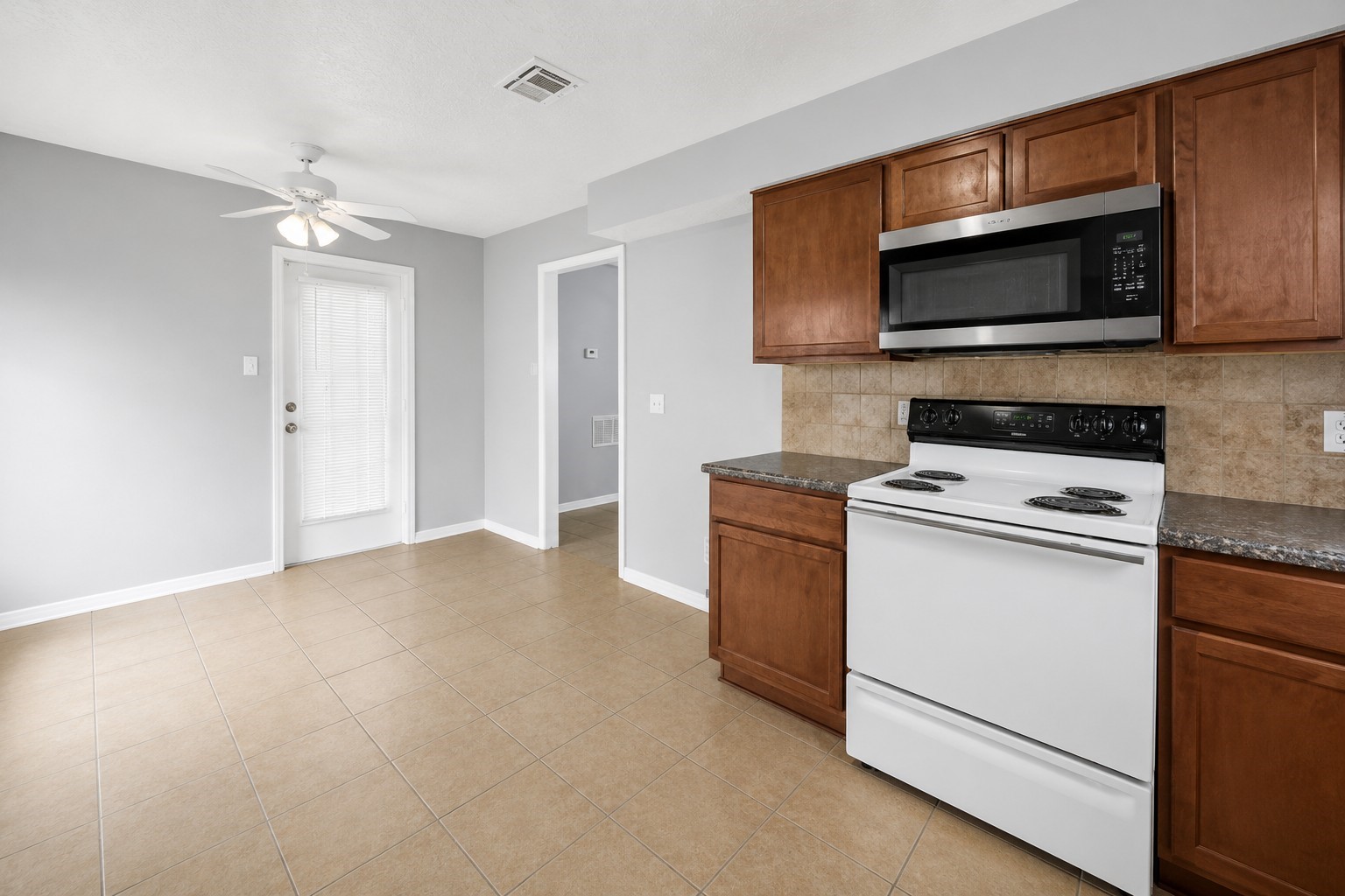 Bright kitchen and dining area featuring ample cabinet space, tile flooring, and convenient garage access. Bright kitchen and dining area featuring ample cabinet space, tile flooring, and convenient garage access.