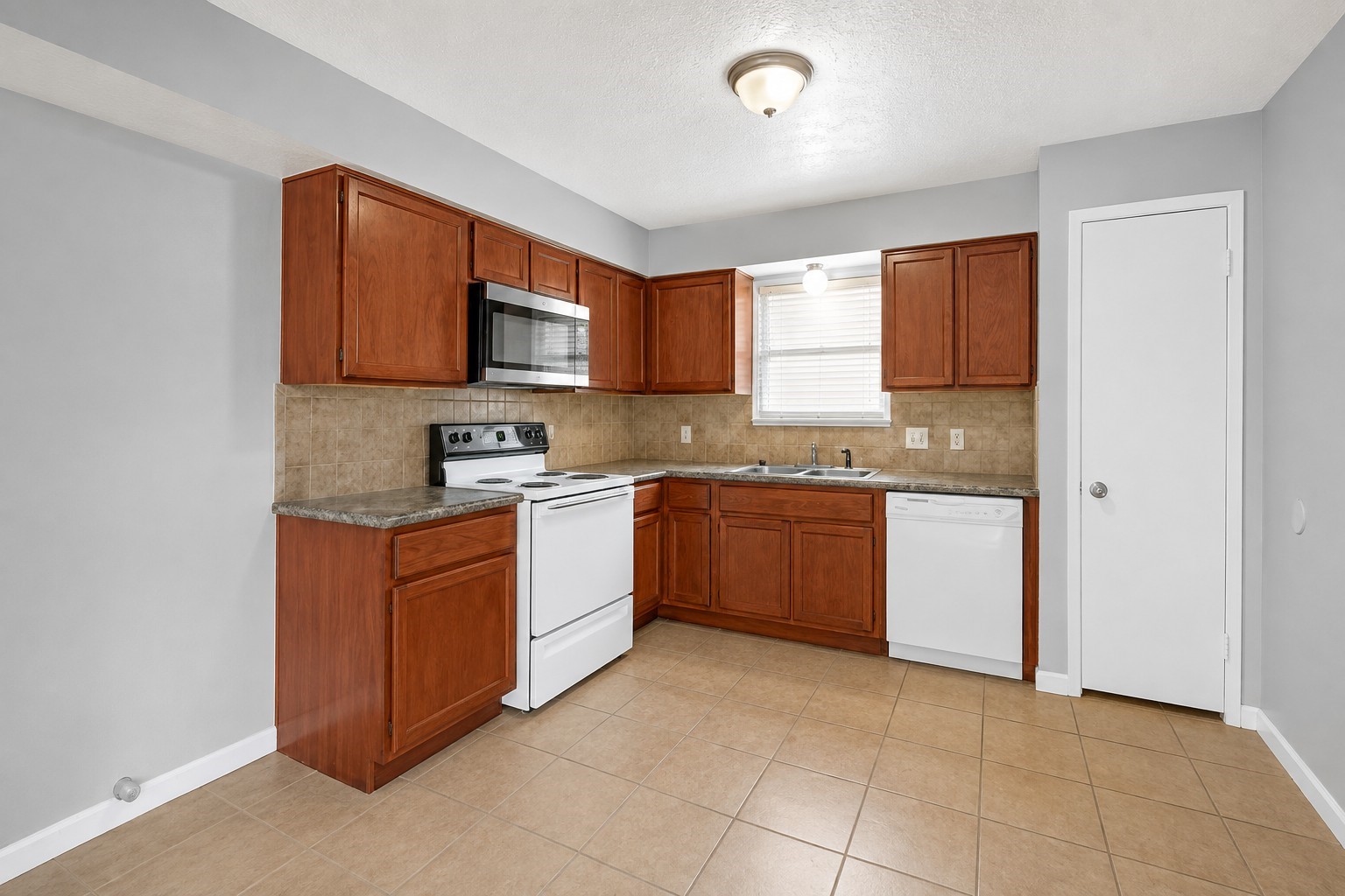 Functional kitchen featuring generous cabinet and counter space, with a window over the sink providing natural light. Functional kitchen featuring generous cabinet and counter space, with a window over the sink providing natural light.