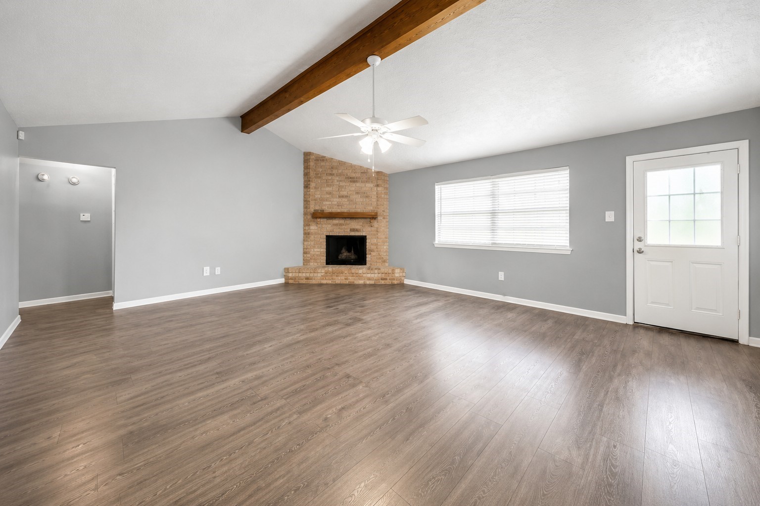Spacious living area featuring vaulted ceilings, exposed wood beam, brick fireplace, and plenty of natural light. Spacious living area featuring vaulted ceilings, exposed wood beam, brick fireplace, and plenty of natural light.