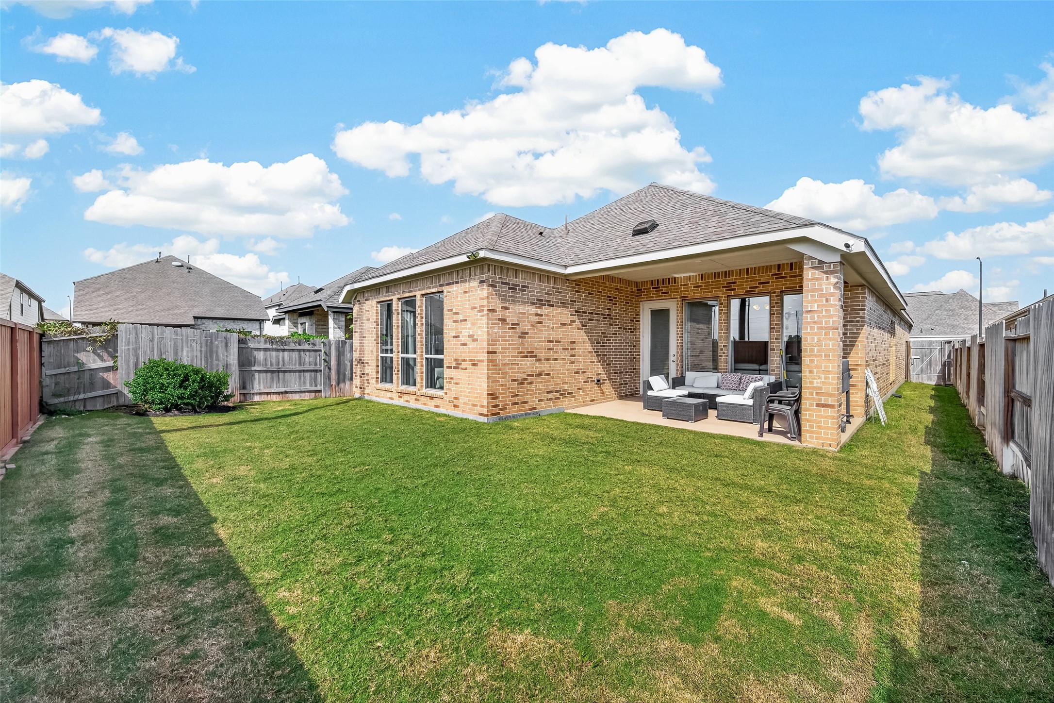 This backyard with covered patio offers a generous amount of open space, perfect for outdoor activities, gardening, or future enhancements.