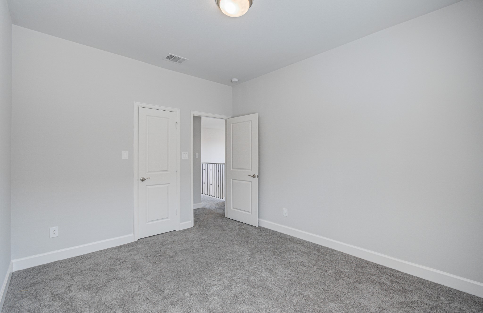 Charming third bedroom with soft gray carpeting, fresh neutral walls, and a sleek light fixture.
