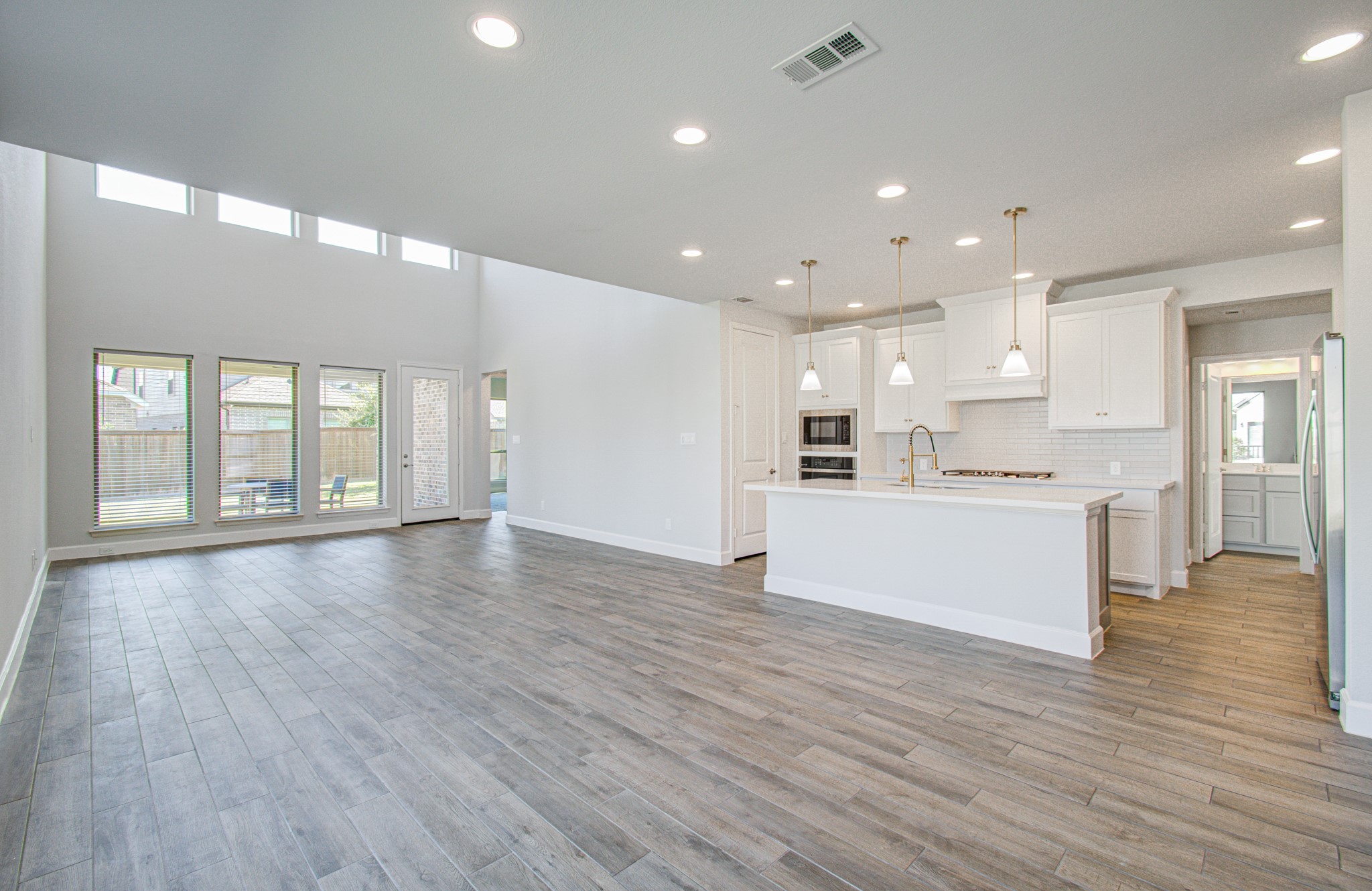 Spacious open-concept living area with high ceilings, abundant natural light, and a modern kitchen featuring sleek cabinetry and pendant lighting.