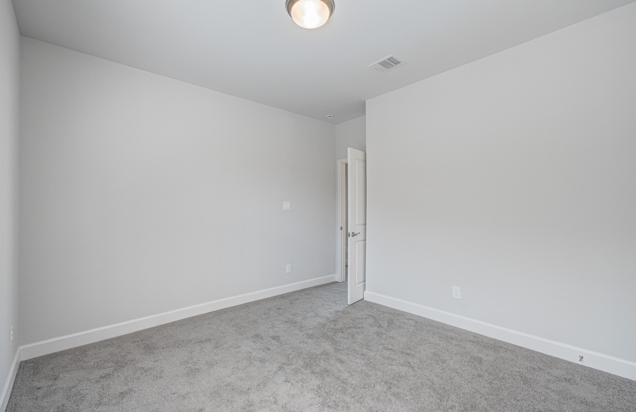 Bright and inviting fourth bedroom featuring soft carpet flooring, neutral walls, and a sleek ceiling light, providing a perfect canvas for personal touches.