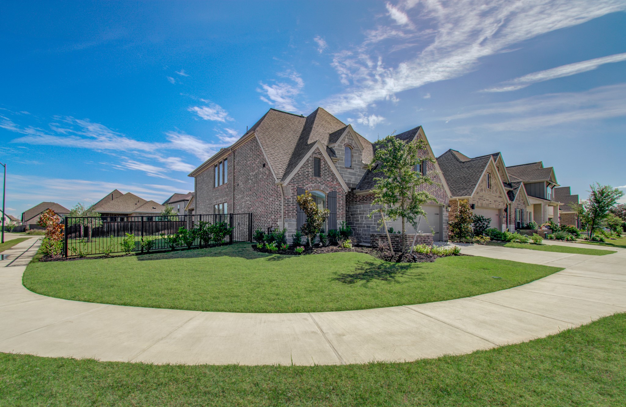 Elegant two-story brick home on a spacious corner lot, featuring a well-maintained lawn and charming landscaping.