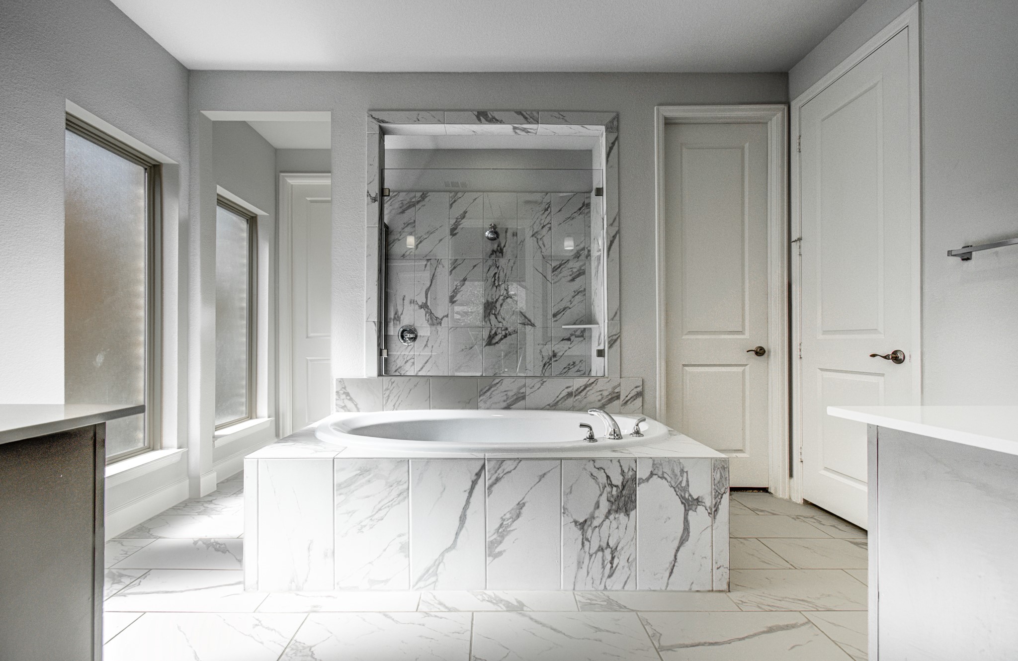 Primary bathroom featuring an elegant tile-surround jetted tub, large walk-in shower, and abundant natural light.