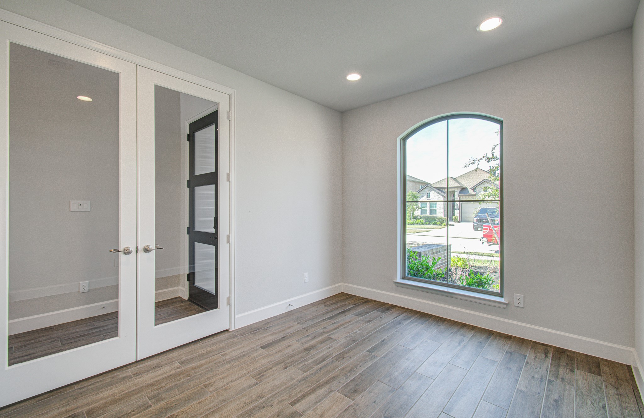 Bright and inviting office/flex room with elegant flooring, a large arched window providing ample natural light, and stylish glass double doors for a modern touch. Bright and inviting office/flex room with elegant flooring, a large arched window providing ample natural light, and stylish glass double doors for a modern touch.