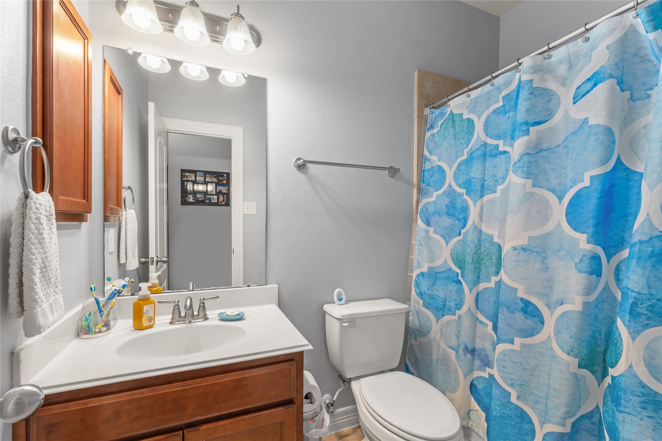Bright and welcoming bathroom with modern fixtures, featuring a stylish shower curtain, a sleek vanity with ample storage, and elegant lighting.