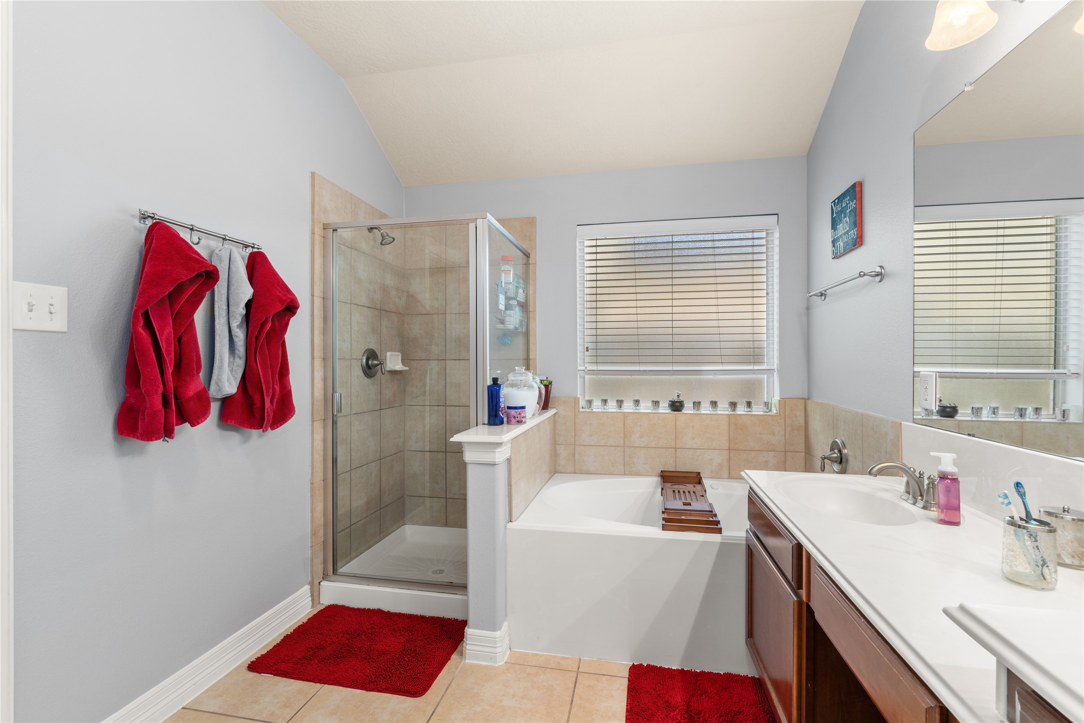 Bright and inviting bathroom featuring a spacious glass-enclosed shower, elegant soaking tub, and dual sinks with ample counter space.
