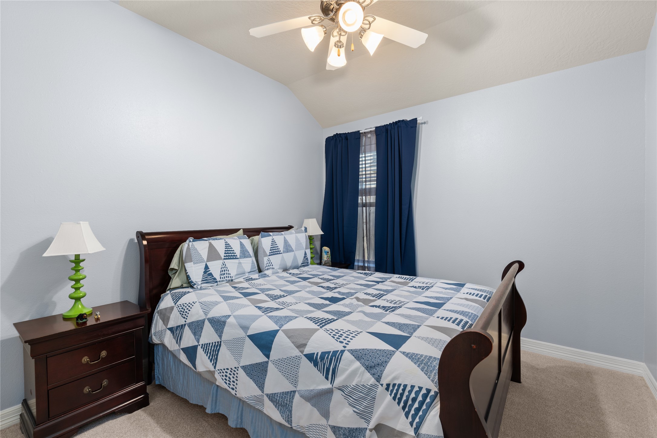 Cozy bedroom featuring a comfortable bed with a geometric quilt, complemented by rich wooden furniture and soft lighting.