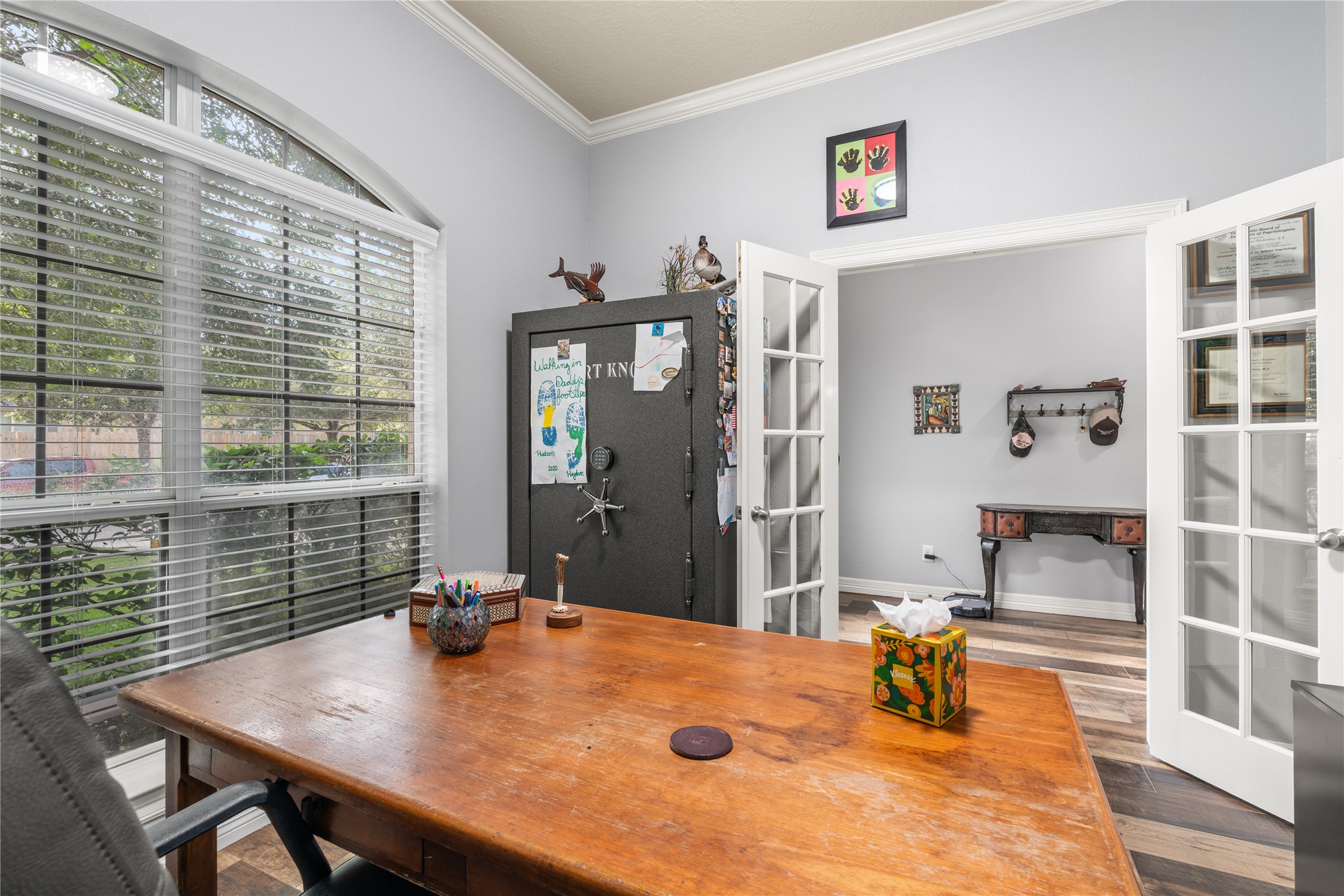 Bright home office featuring French doors, a large window for natural light, and elegant crown molding, creating a welcoming and productive space.