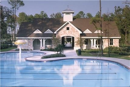 Stunning community pool with a charming clubhouse backdrop, surrounded by lush greenery for a perfect blend of relaxation and leisure.