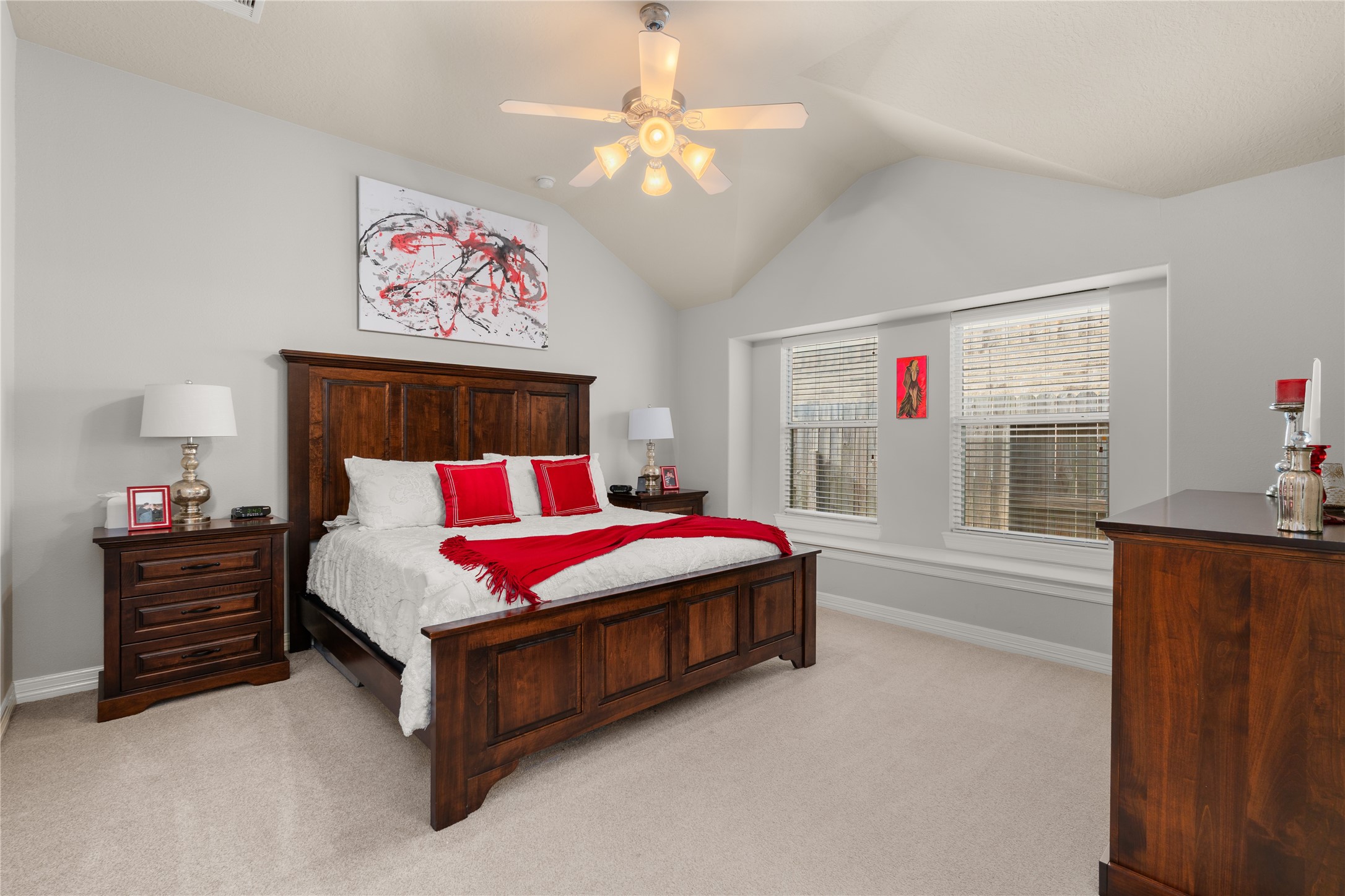 Spacious bedroom with vaulted ceilings, featuring a cozy wooden bed frame and matching furniture, complemented by modern decor and natural light from large windows.