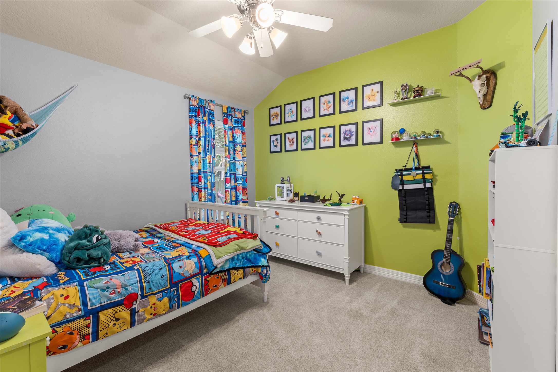 Bright and cheerful bedroom with playful decor, featuring colorful curtains, themed bedding, and a vibrant green accent wall adorned with framed art.