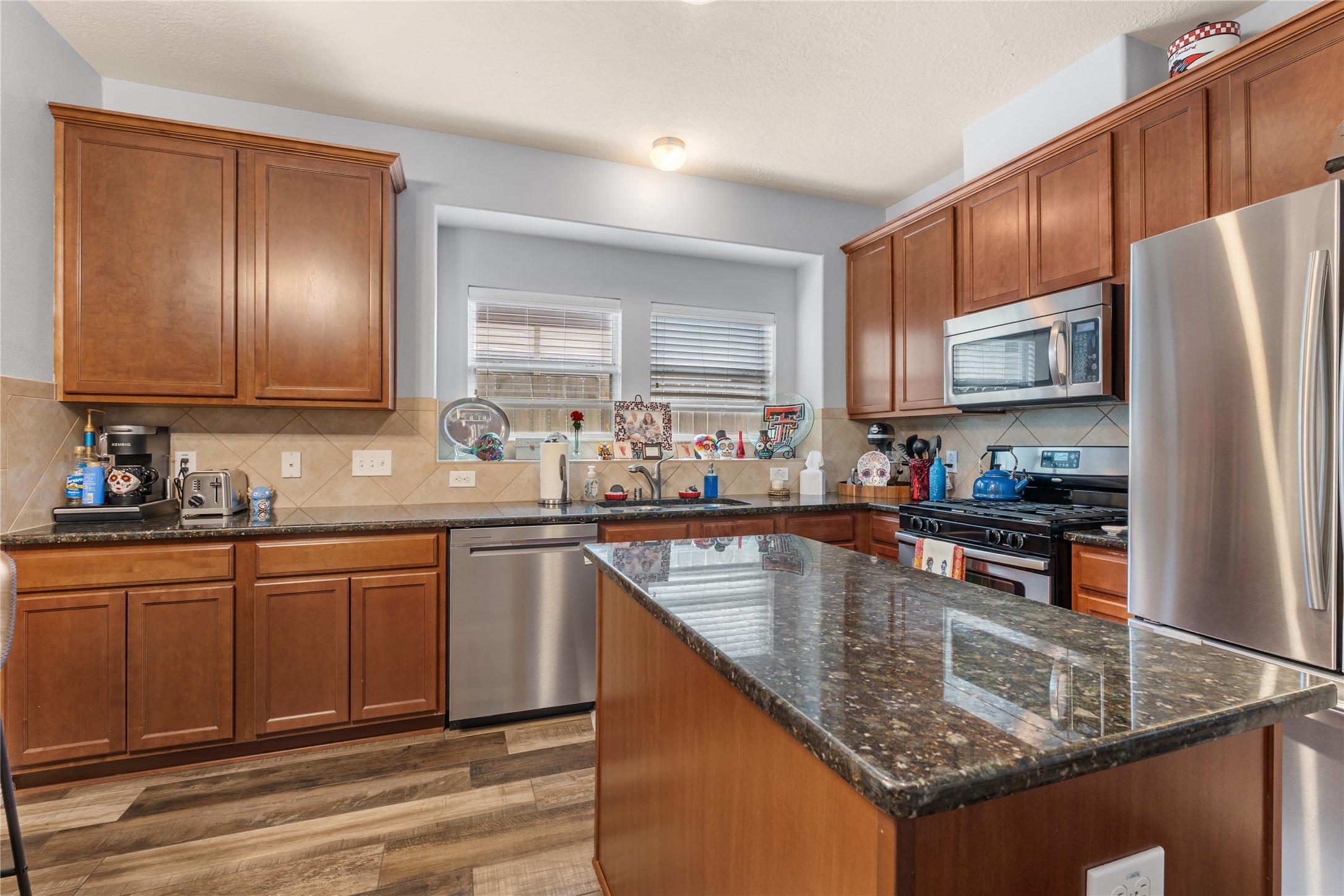 A modern kitchen featuring sleek stainless steel appliances, rich wood cabinetry, and a spacious granite-topped island with ample counter space for meal prep and entertaining.
