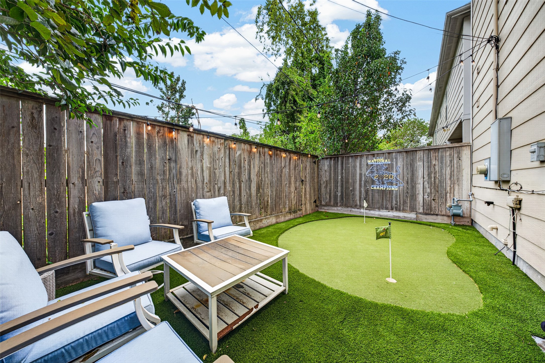 Low-maintenance backyard with artificial turf, outdoor seating, and a private putting greenperfect for relaxing or practicing your short game.