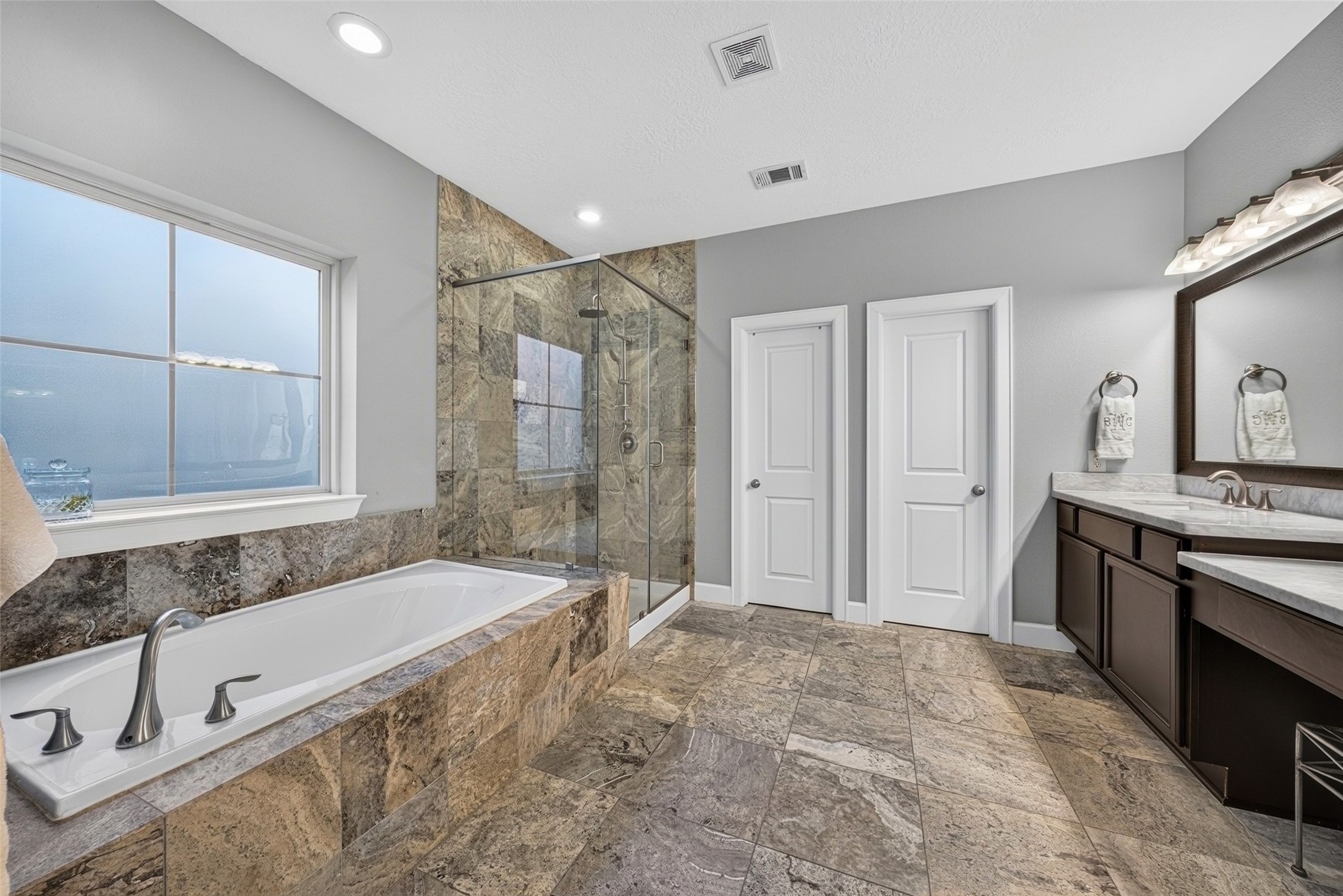 Primary bath highlighting the soaking tub, glass-enclosed shower, and elegant tile finishes.